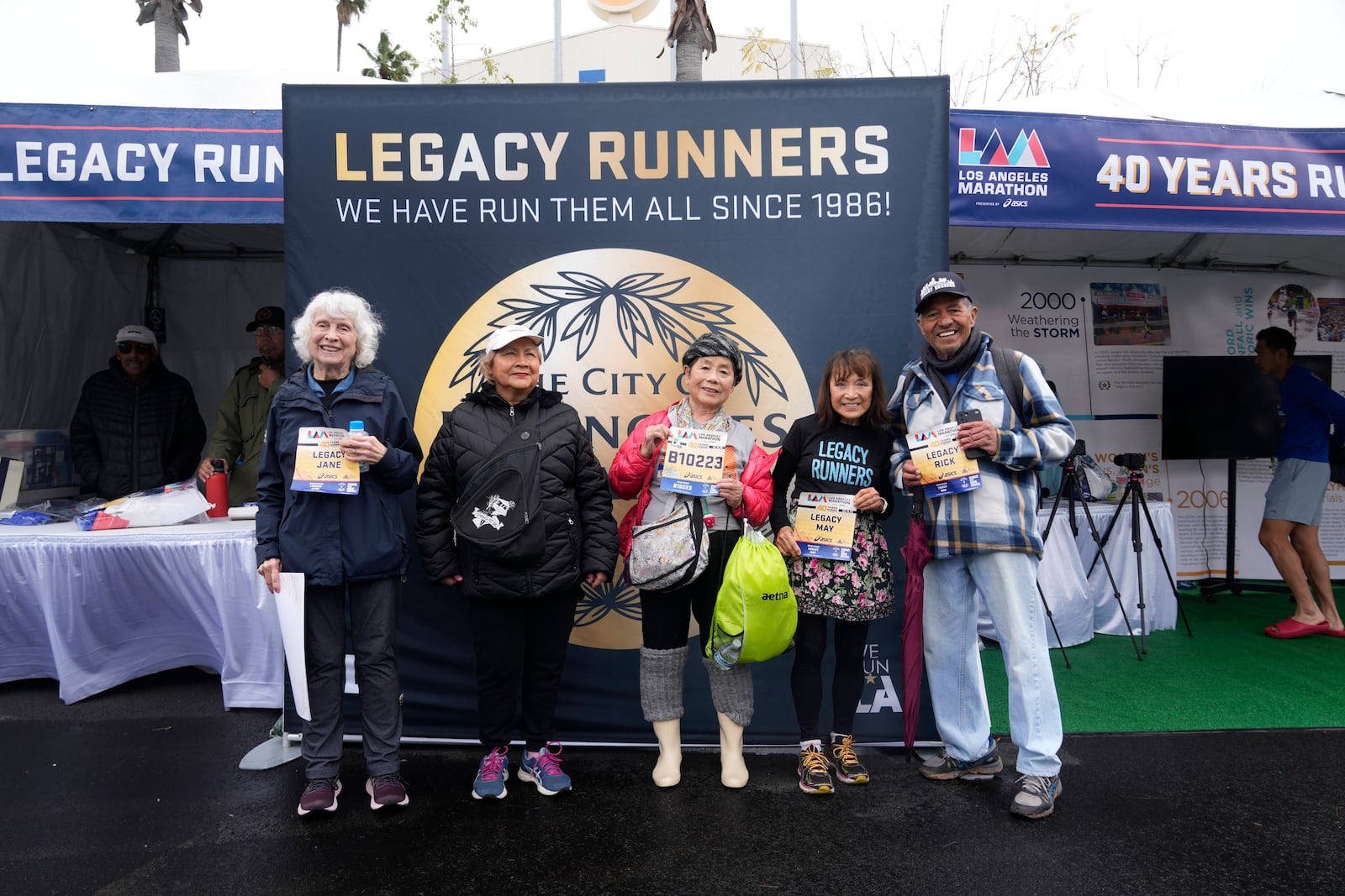 From left, runners Masako Higuchi, 83, third from left, and May DuBois, fourth from left, take photos with fellow runners ahead of the Los Angeles Marathon at the Lifestyle Expo at Dodger Stadium, Friday, March 14, 2025 in Los Angeles. (AP Photo/Damian Dovarganes)