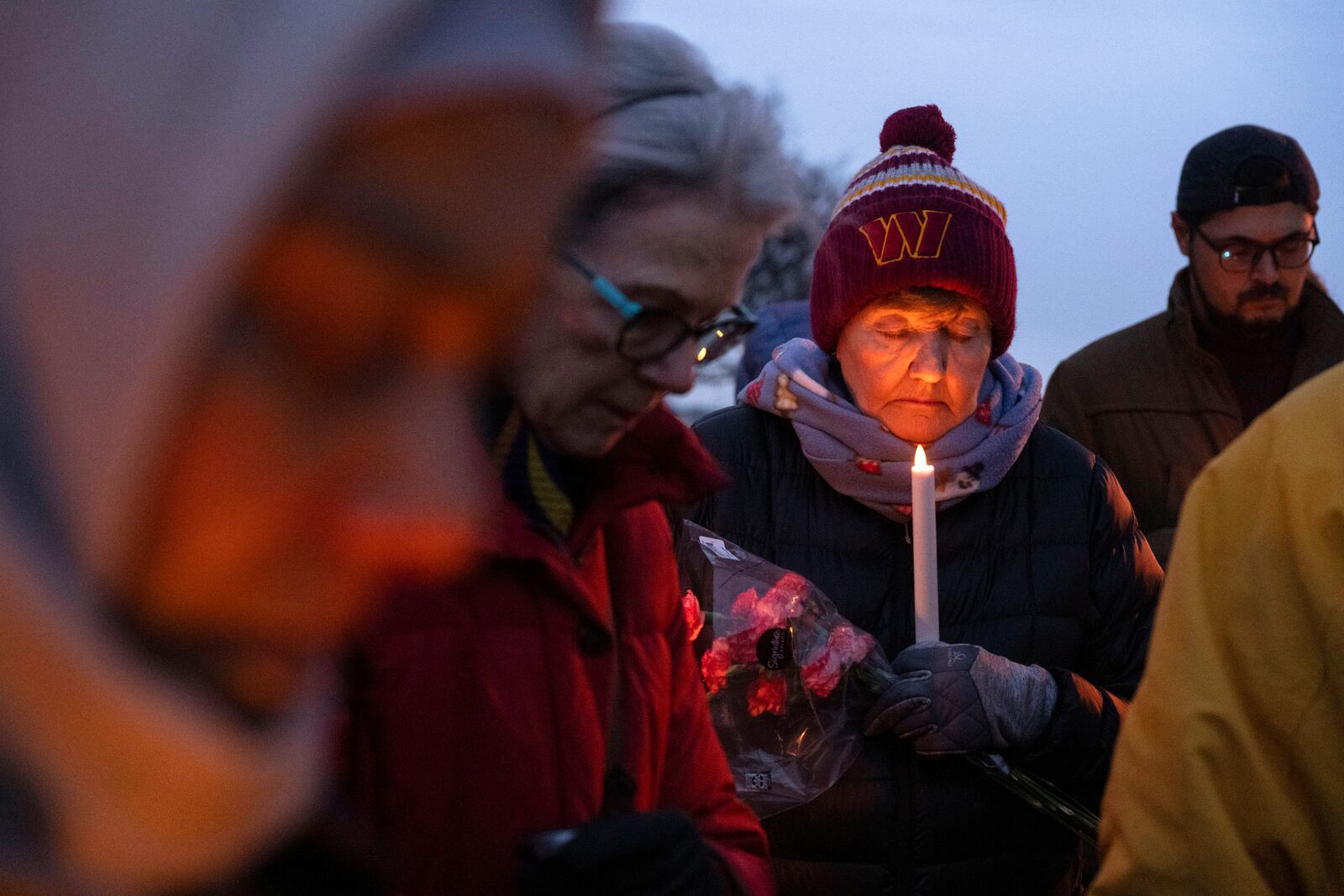 Sandy Woods closes her eyes for prayer during a candlelight vigil, Wednesday, Feb. 5, 2025 in Alexandria, Va., for the victims of the mid-air collision of an American Airlines jet and a Black Hawk helicopter at Reagan National Airport. (AP Photo/Kevin Wolf)