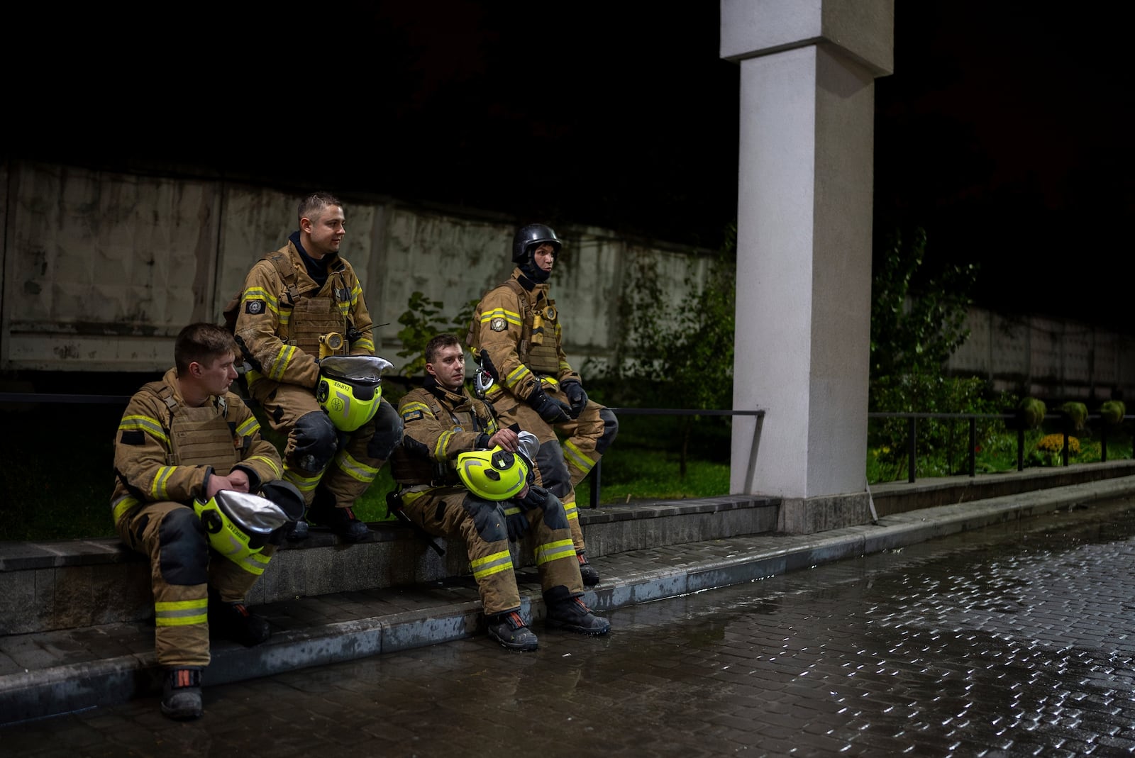 Firefighters rest on a curb during after responding to a Russian attack that killed a teenager in Kyiv, Ukraine, early Saturday, Oct. 26, 2024. (AP Photo/Alex Babenko)