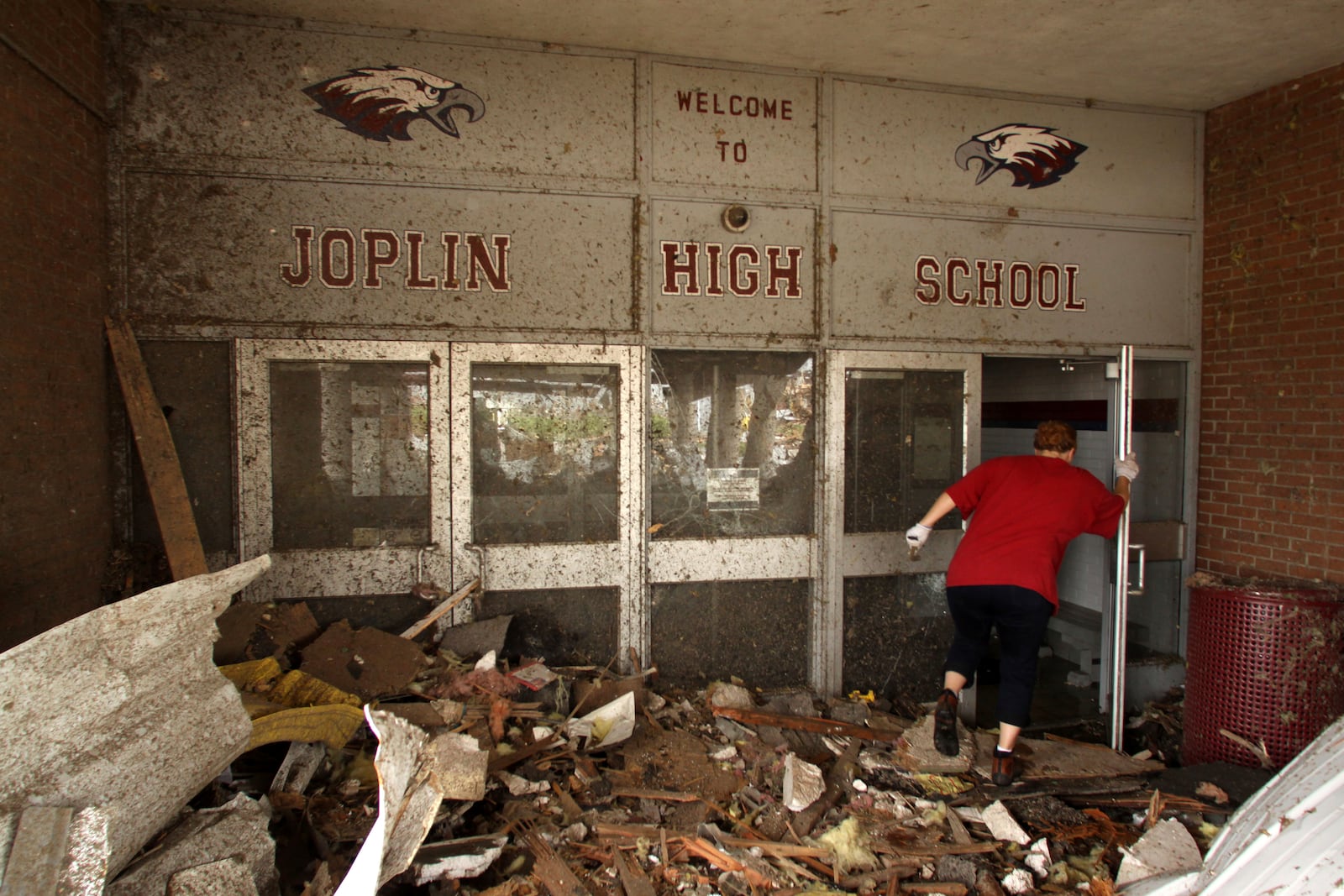 FILE- A woman makes her way into the damaged main entrance of Joplin High School in Joplin, Mo., Tuesday, May 24, 2011. (AP Photo/Mark Schiefelbein, File)