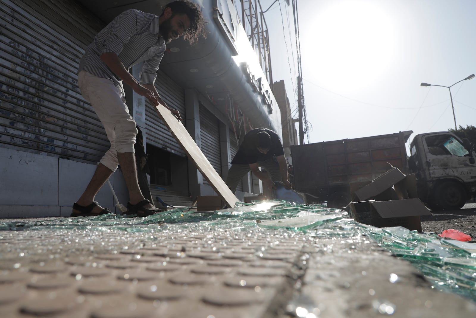 Yemenis clean debris in front of their shops after a U.S. airstrikes in Sanaa, Yemen, Sunday, March 16, 2025. (AP Photo/Osamah Abdulrahman)