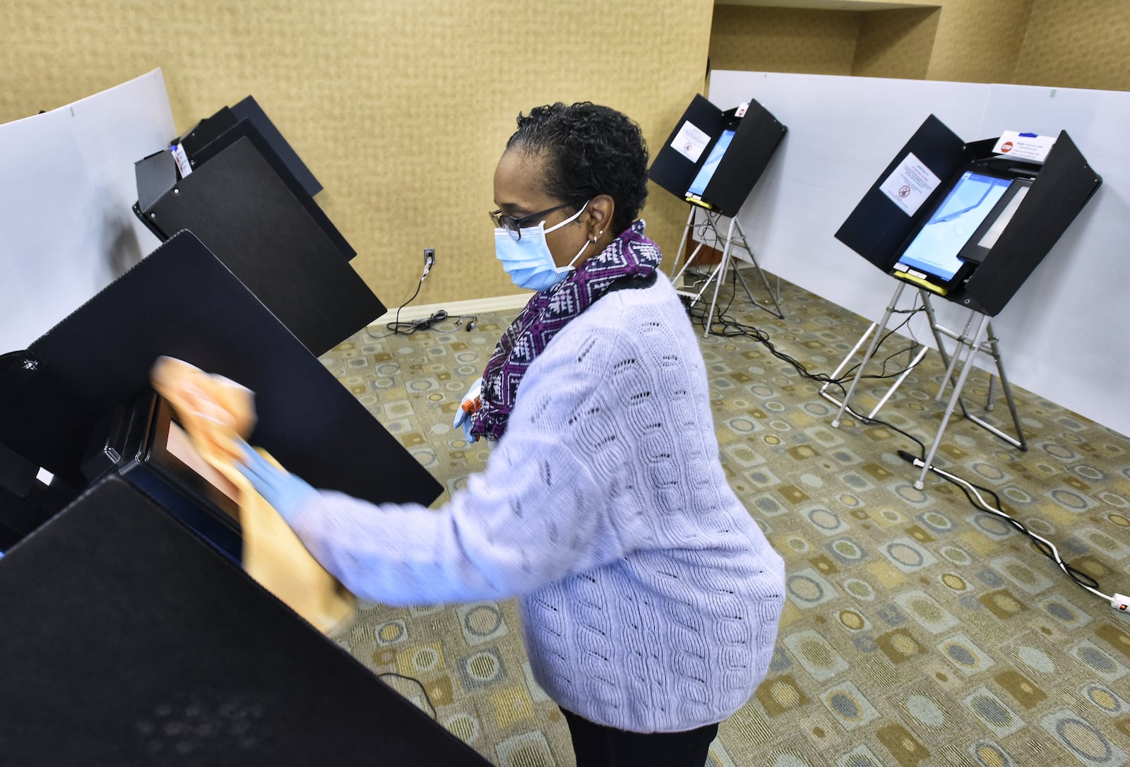 Butler County Board of Elections volunteer Jillynn Whitlow cleans voting machines on the first day of early voting Tuesday, October 6, 2020 in Hamilton. NICK GRAHAM / STAFF