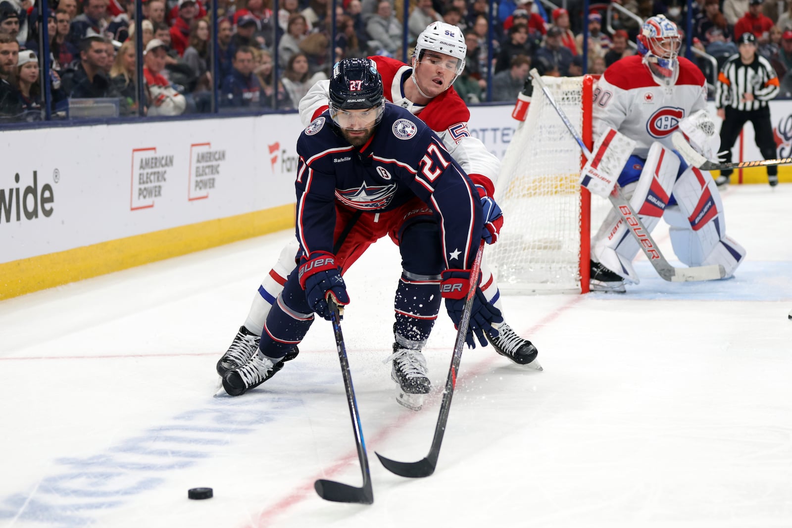 Columbus Blue Jackets defenseman Zachary Aston-Reese, left, reaches for the puck in front of Montreal Canadiens defenseman Justin Barron during the second period of an NHL hockey game in Columbus, Ohio, Wednesday, Nov. 27, 2024. (AP Photo/Paul Vernon)