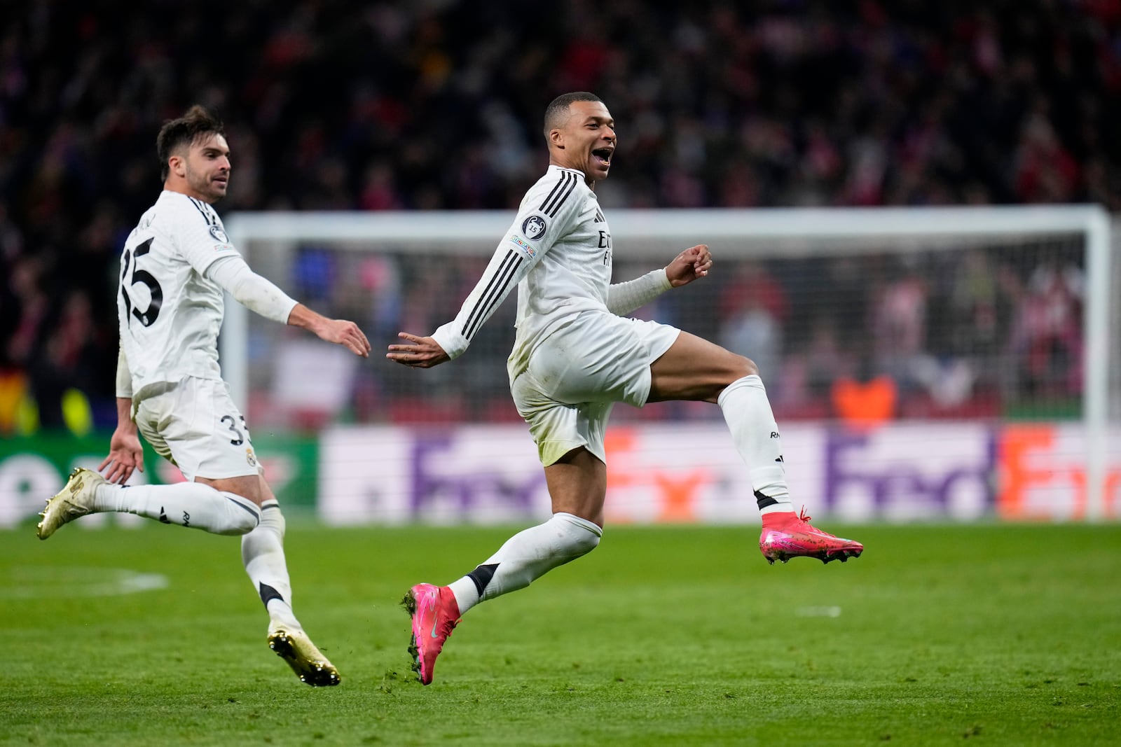 Real Madrid's Kylian Mbappe and Raul Asencio, left, run celebrating after a penalty shootout at the end of the Champions League round of 16, second leg, soccer match between Atletico Madrid and Real Madrid at the Metropolitano stadium in Madrid, Spain, Wednesday, March 12, 2025. (AP Photo/Manu Fernandez)