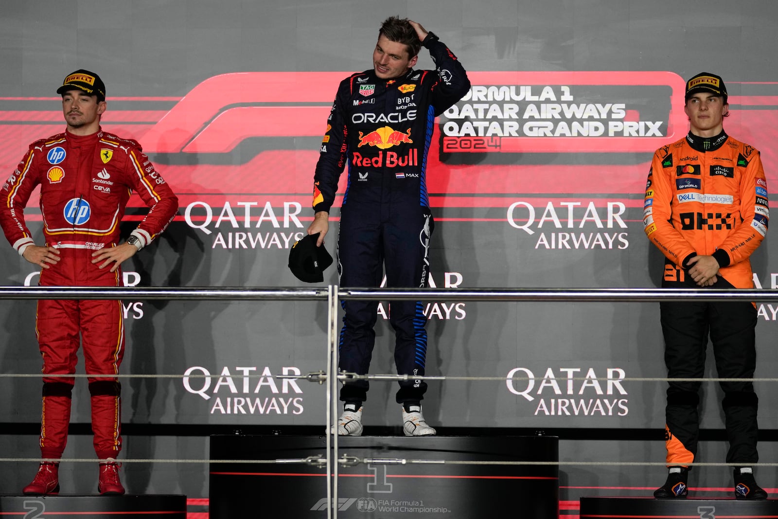 From the left, second-aced Ferrari driver Charles Leclerc of Monaco, first-placed Red Bull driver Max Verstappen of the Netherlands, and third-placed McLaren driver Oscar Piastri of Australia stand on the podium during the Qatar Formula One Grand Prix at the Lusail International Circuit in Lusail, Qatar, Sunday, Dec. 1, 2024. (AP Photo/Altaf Qadri)