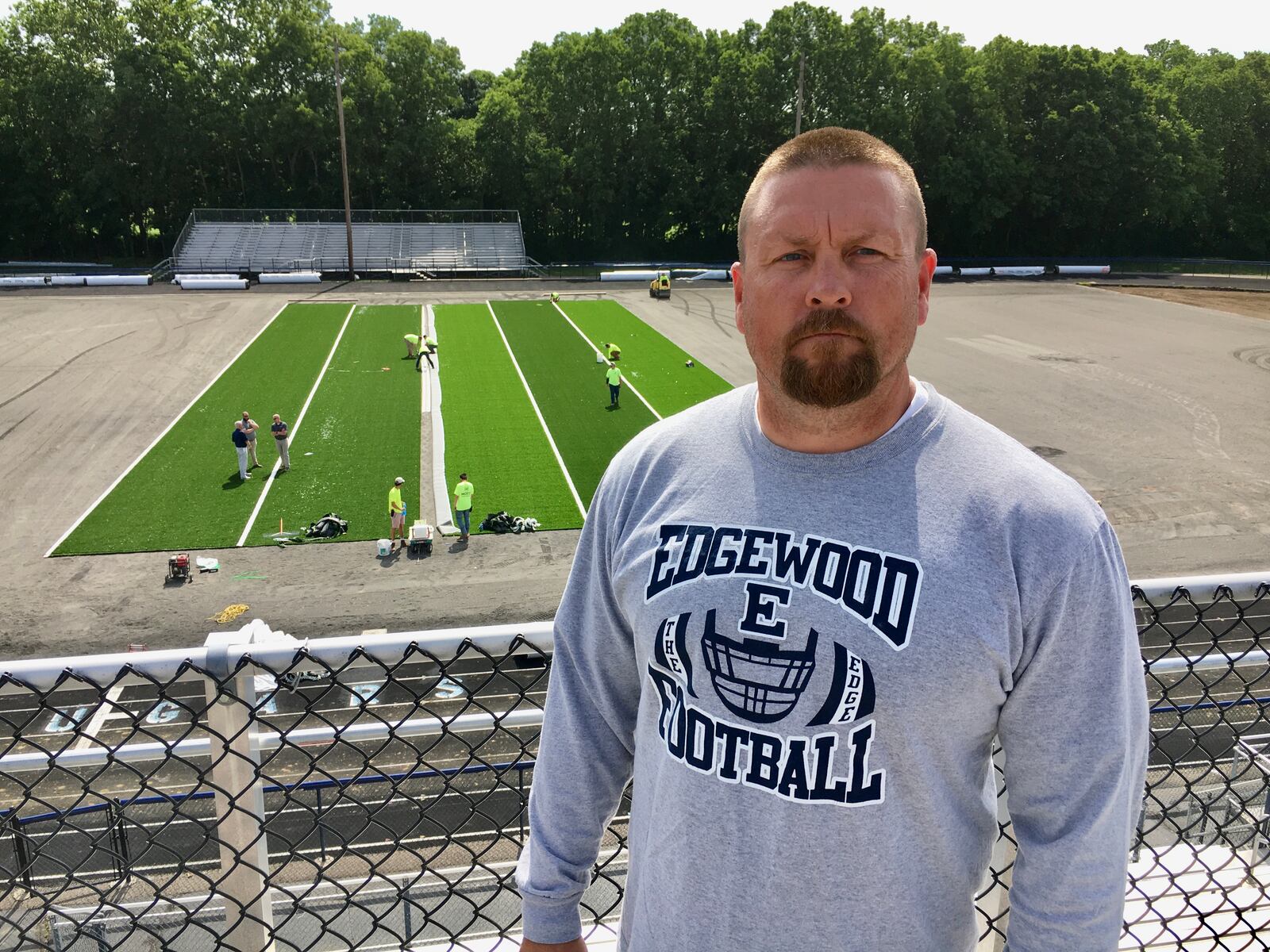 Edgewood High School Head Football Coach Scott Clemmons climbed on to the top of Kumler Stadium's press box to take a better look at the new synthetic turf being rolled out this summer. The turf is part of a $1.2 million stadium renovation project, which includes a new track, and is expected to be done by late August. (Photo By Michael D. Clark\Journal-News)