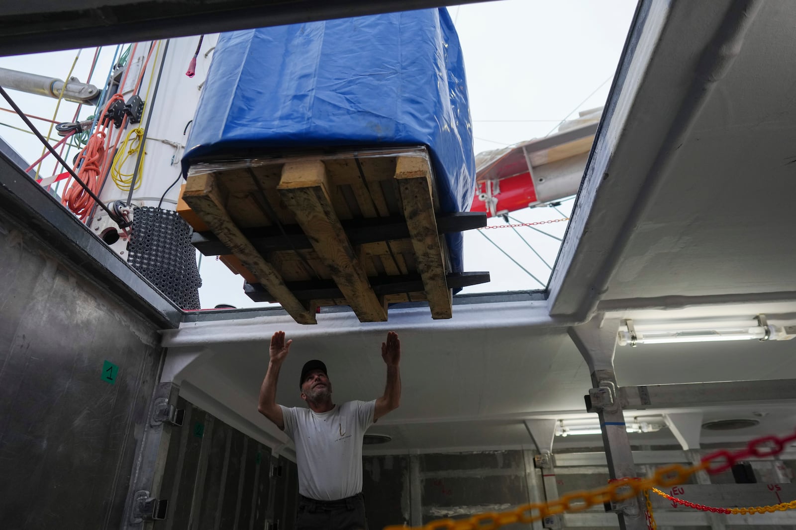 Sailor Goulwen Josse helps to place a pallet in the sailboat's 'Grain de Sail II' hold at the port of Saint Malo, western France, Nov. 8, 2024. (AP Photo/Thibault Camus)