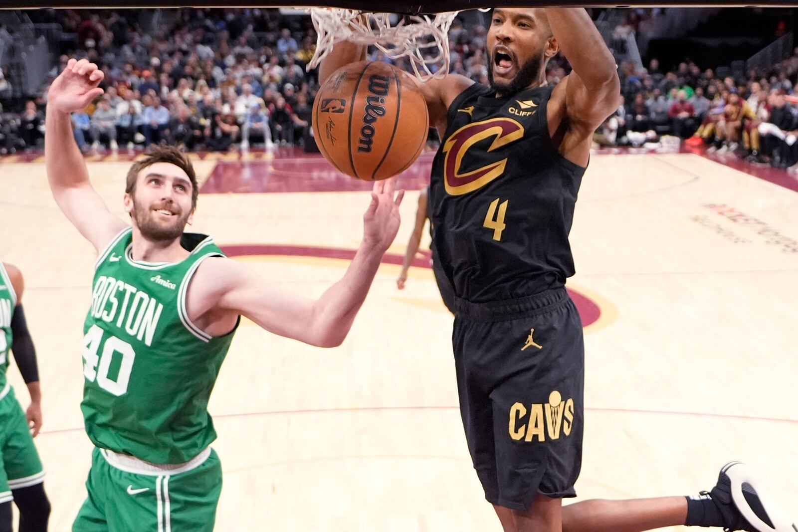 Cleveland Cavaliers forward Evan Mobley (4) dunks in front of Boston Celtics center Luke Kornet (40) in the second half of an NBA basketball game, Tuesday, Feb. 4, 2025, in Cleveland. (AP Photo/Sue Ogrocki)