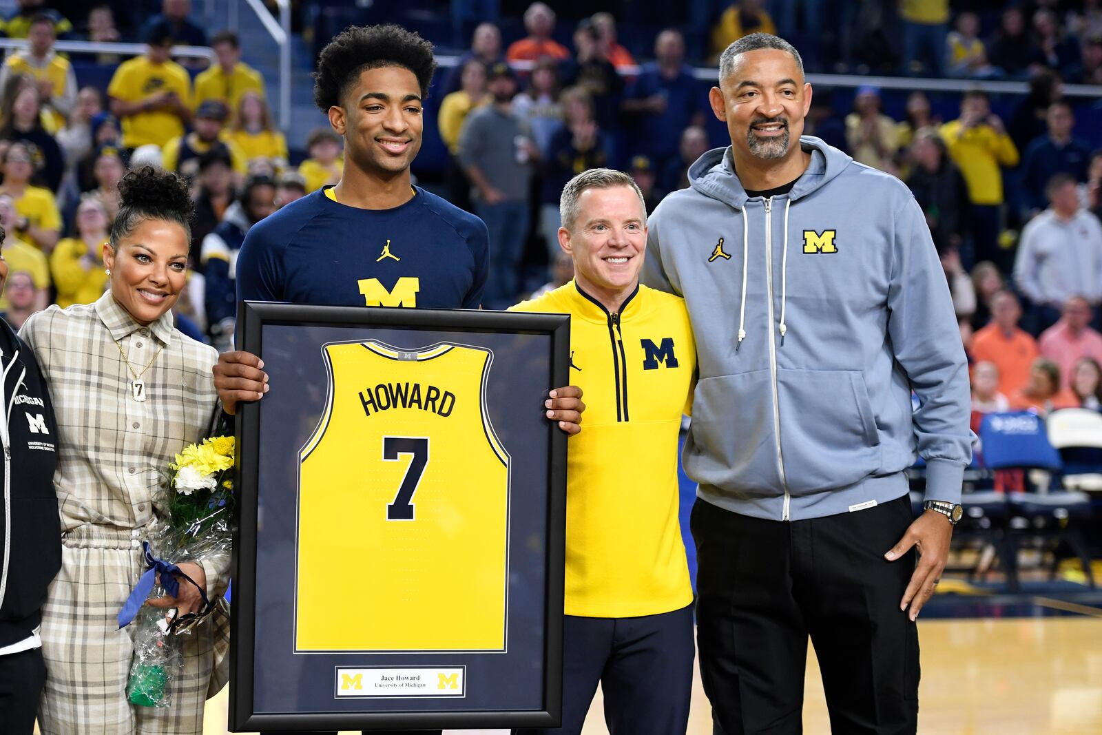 Michigan's Jace Howard (7) stands with his mother, Jenine Howard, left, head coach Dusty May, second from right, and his father, former Michigan head coach Juwan Howard during a senior day ceremony before an NCAA college basketball game against Illinois, Sunday, March 2, 2025, in Ann Arbor, Mich. (AP Photo/Jose Juarez)