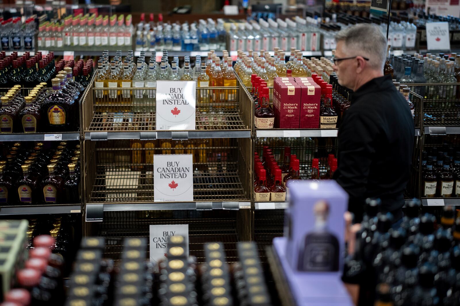 A liquor store employee looks at a sign placed in the American whiskey section at a B.C. Liquor Store after top selling American made products have been removed from shelves in Vancouver, B.C., Sunday, Feb. 2, 2025. (Ethan Cairns/The Canadian Press via AP)