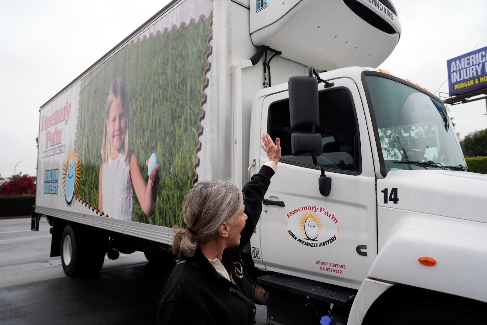 Rosemary Farm family representative Lisa Stothart welcomes a company truck delivering hundreds of thousands of fresh eggs donated by Rosemary Farm to feed first responders and those in need in the community at the Los Angeles Food Regional Bank in City of Industry, Calif., on Wednesday, Feb. 12, 2025. (AP Photo/Damian Dovarganes)