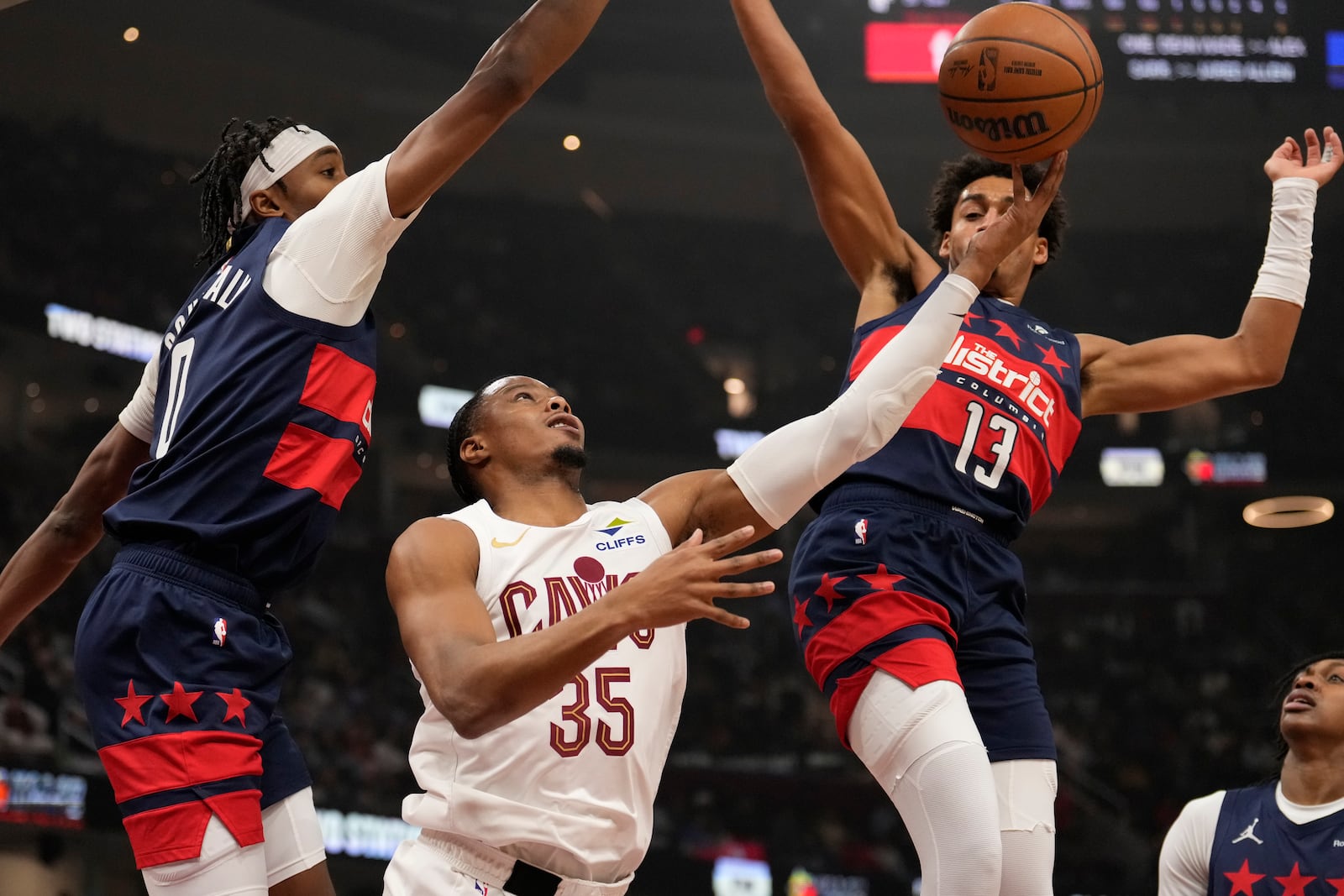 Cleveland Cavaliers forward Isaac Okoro (35) goes to the basket between Washington Wizards guard Bilal Coulibaly (0) and guard Jordan Poole (13) in the first half of an NBA basketball game, Friday, Dec. 13, 2024, in Cleveland. (AP Photo/Sue Ogrocki)