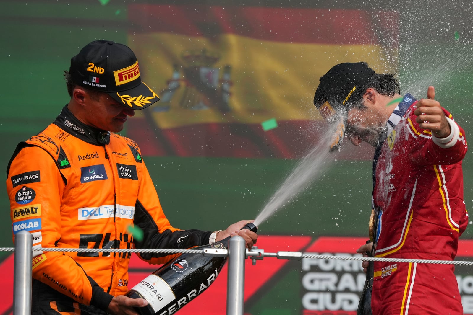 Ferrari driver Carlos Sainz of Spain gets champagne sprayed in his face by second placed McLaren driver Lando Norris of Britain after winning the Formula One Mexico Grand Prix auto race at the Hermanos Rodriguez racetrack in Mexico City, Sunday, Oct. 27, 2024. (AP Photo/Fernando Llano)