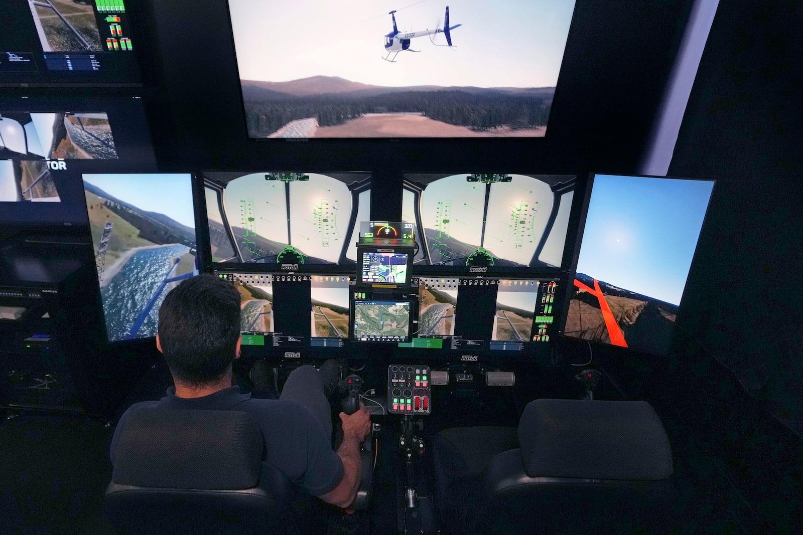 Joao Magioni, Chief Flight Officer of Rotor Technologies, flies a simulated unmanned semi-autonomous helicopter from the company's remote operations center, Monday, Nov. 11, 2024, in Nashua, N.H. The interface can also be used as a ground control station for real-time flight operations. (AP Photo/Charles Krupa)