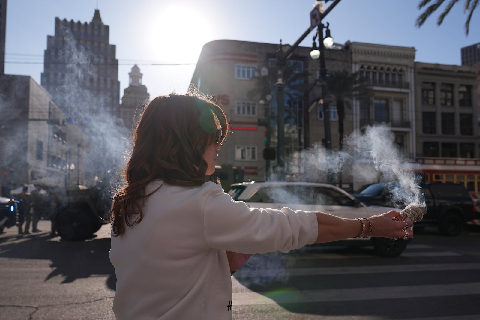 Stephanie Drake burns sage on Canal and Bourbon Street, Thursday, Jan. 2, 2025 in New Orleans. (AP Photo/George Walker IV)