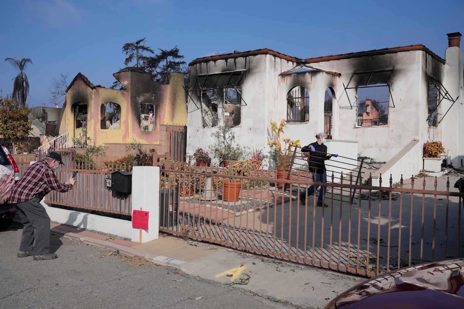 Joel Parkes, a teacher at Los Angeles Unified School District, left, returns to his home with his wife in the aftermath of the Eaton Fire, Sunday, Jan. 19, 2025, in Altadena, Calif. (AP Photo/Damian Dovarganes)