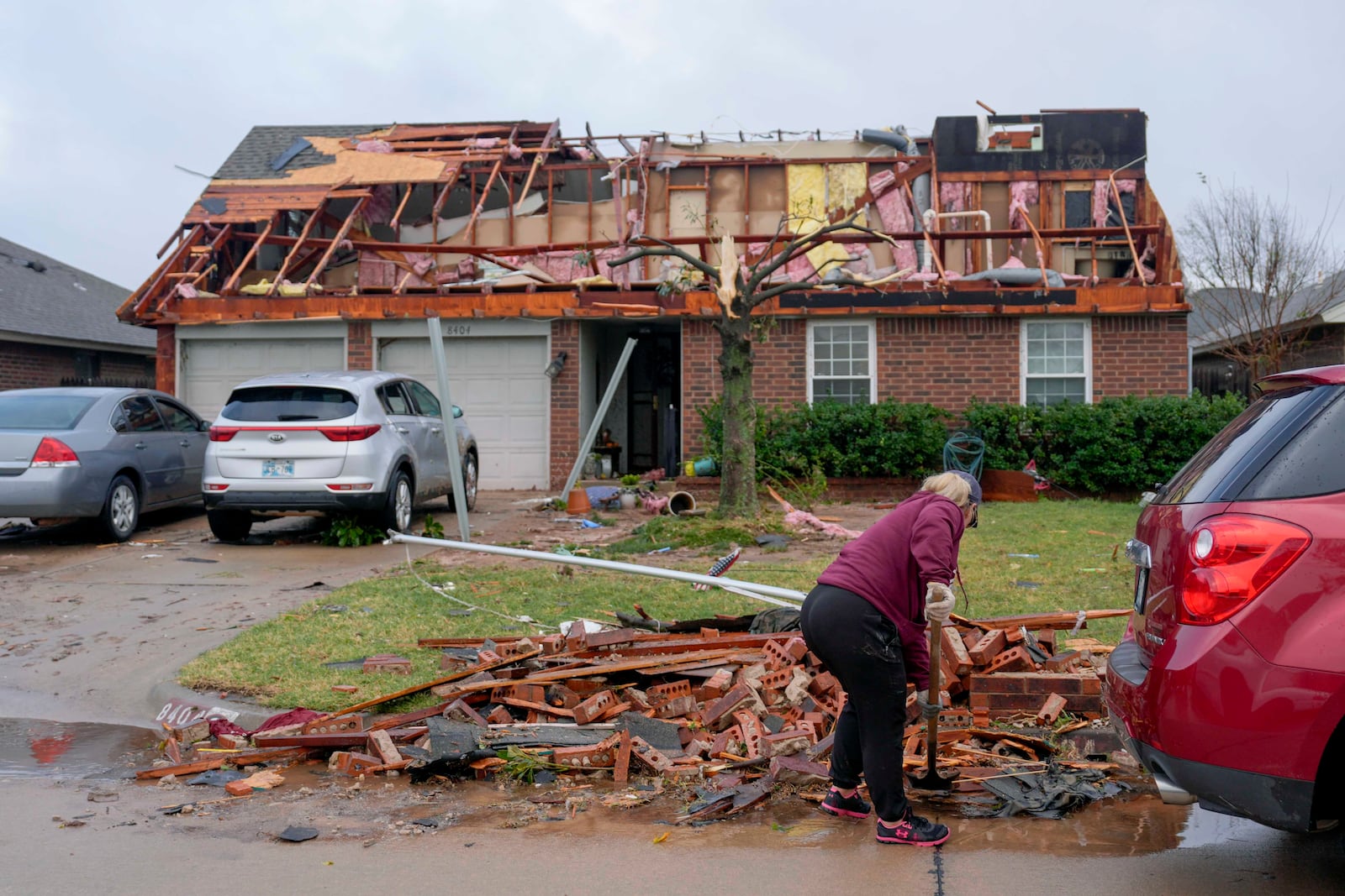 A person cleans up debris by a damaged home on Stonewood Drive after a tornado moved through the area in Oklahoma City, Sunday, Nov. 3, 2024. (Bryan Terry/The Oklahoman via AP)