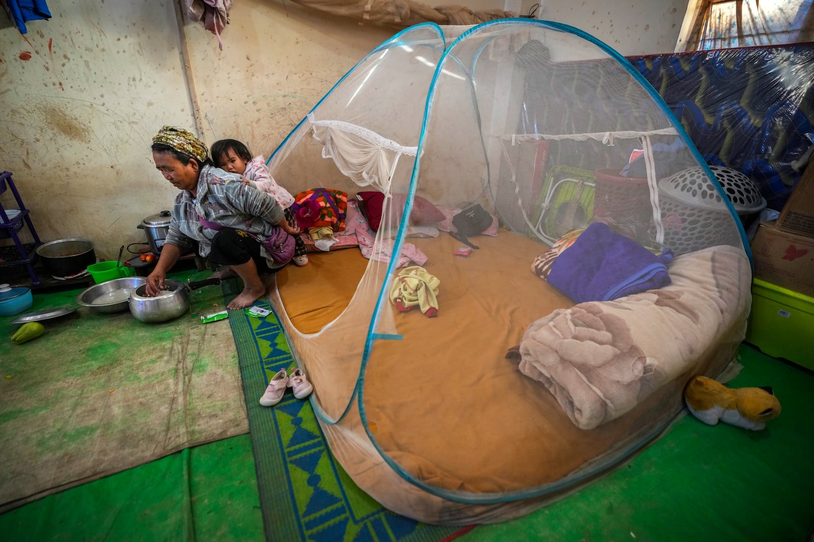 A Kuki tribal woman with a child prepares rice in a relief camp in Kangpokpi, Manipur, Sunday, Dec. 15, 2024. (AP Photo/Anupam Nath)