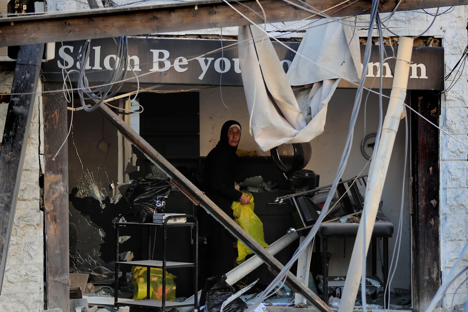 A woman looks on through her hair salon which was destroyed after Israeli airstrikes hit several buildings in Tyre, south Lebanon, Wednesday, Oct. 23, 2024. (AP Photo/Mohammed Zaatari)