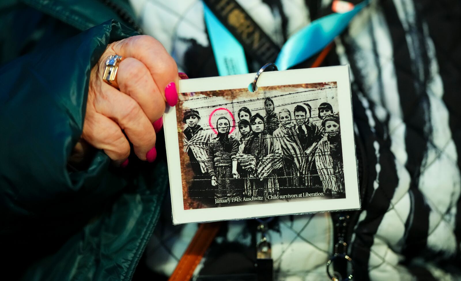 Canadian Holocaust survivor Miriam Ziegler holds up a photo of her (circled) as as she attends the Commemoration Ceremony of the 80th Anniversary of the Liberation of Auschwitz, in Oswiecim, Poland, on Monday, Jan. 27, 2025. (Sean Kilpatrick/The Canadian Press via AP)