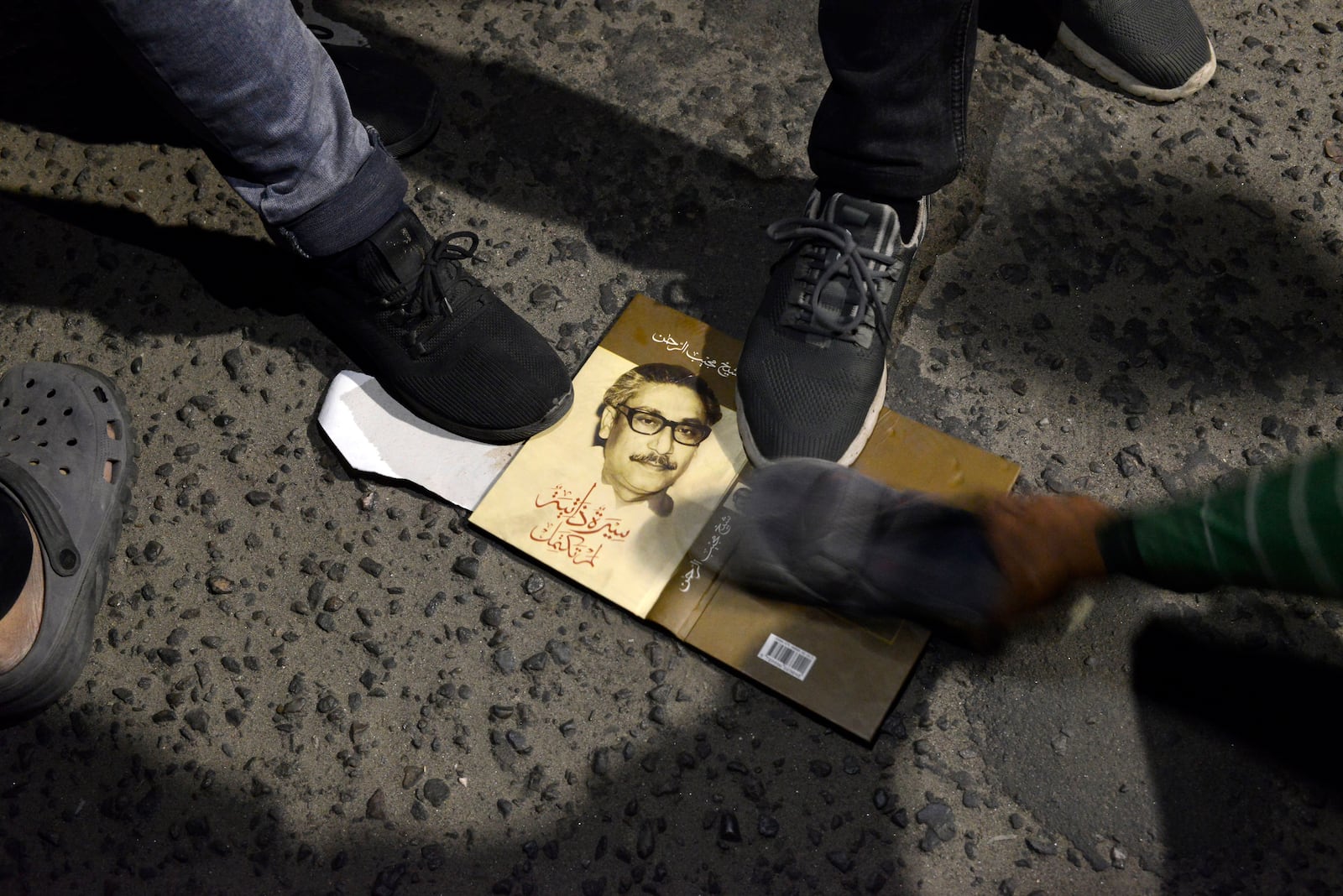 Protesters stomp on a book which shows a portrait of Sheikh Mujibur Rahman, Bangladesh's former leader and the father of the country's ousted Prime Minister Sheikh Hasina, in Dhaka in Dhaka, Bangladesh, Wednesday, Feb. 5, 2025. (AP Photo/Mahmud Hossain Opu)