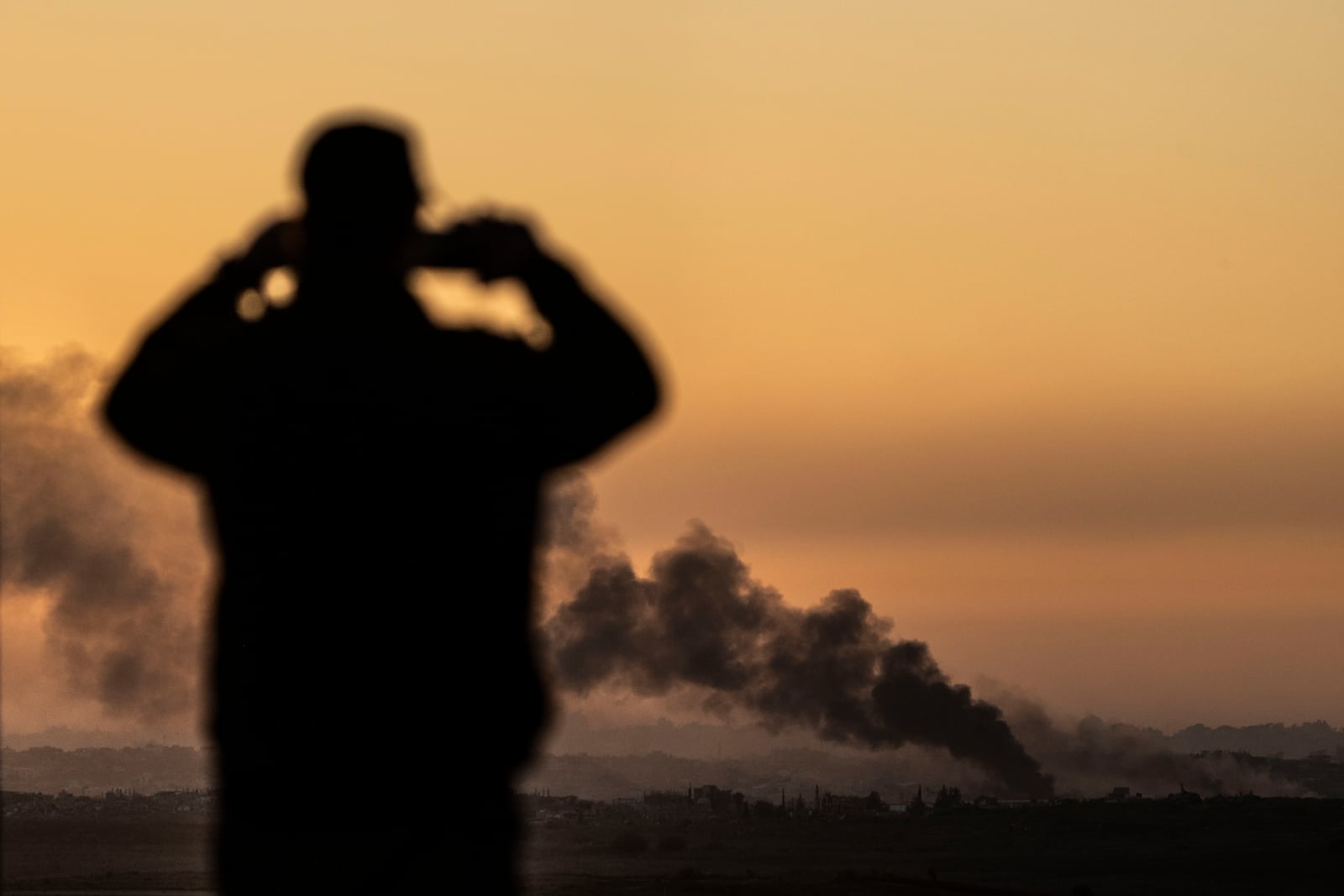 FILE - A man looks at smoke rising following an explosion inside the Gaza Strip, from an observation point in Sderot, southern Israel, on Jan. 13, 2025. (AP Photo/Ariel Schalit, File)