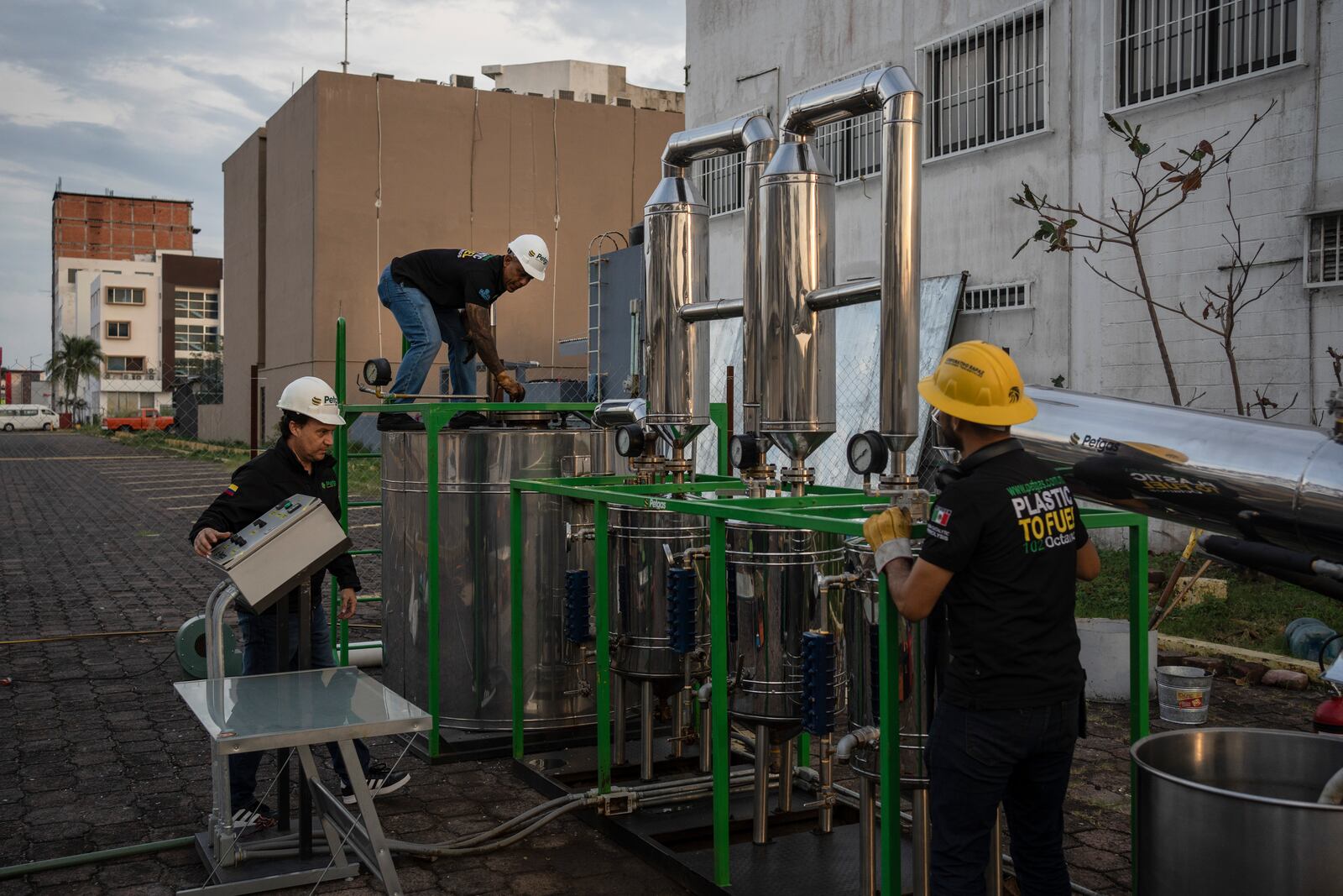 Jesus Cuevas, center, Daniel Rodriguez, left, and Carlos Parraguirre Diaz, right, run a demonstration operation of Petgaserita, a non-catalytic pyrolysis machine that converts plastic into fuel, in Boca del Rio, Veracruz, Mexico, Jan. 4, 2025. (AP Photo/Felix Marquez)