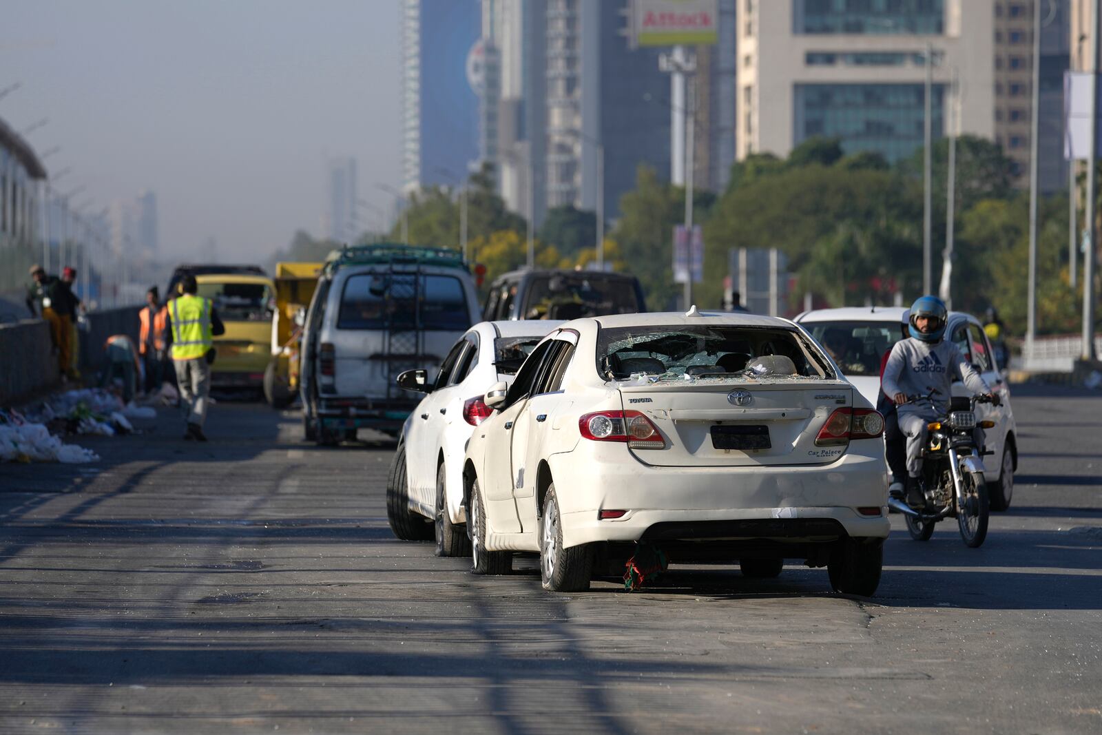 Workers clean an area near the damaged vehicles left behind by supporters of imprisoned former Prime Minister Imran Khan's Pakistan Tehreek-e-Insaf party, when security forces launched an operation Tuesday night to disperse them, in Islamabad, Pakistan, Wednesday, Nov. 27, 2024. (AP Photo/Anjum Naveed)