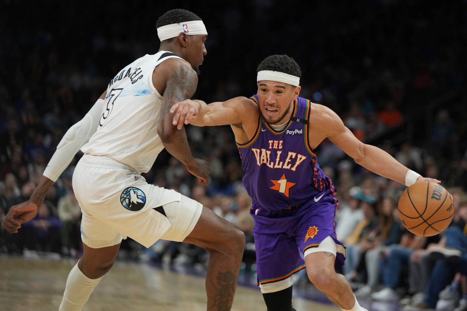 Phoenix Suns guard Devin Booker (1) drives on Minnesota Timberwolves forward Jaden McDaniels during the second half of an NBA basketball game, Sunday, March 2, 2025, in Phoenix. (AP Photo/Rick Scuteri)