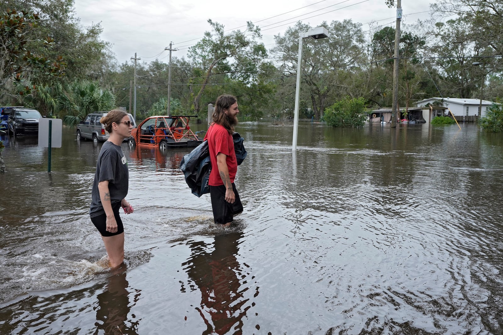 Kaylee Swanson, left, and Connor Hughes walk through floodwaters from the Alafia river caused by Hurricane Milton Friday, Oct. 11, 2024, in Lithia, Fla. (AP Photo/Chris O'Meara)