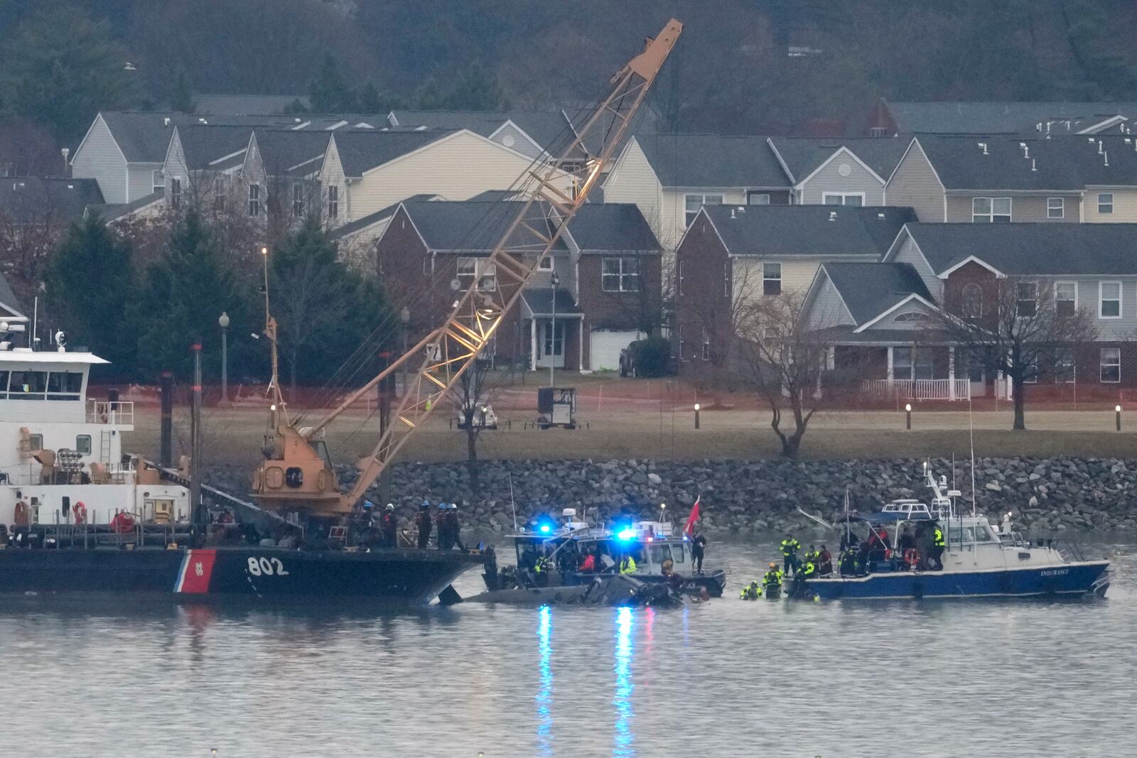 A Coast Guard vessel with a crane and members of a dive team are pictured working near the wreckage of a Black Hawk helicopter in the Potomac River from Ronald Reagan Washington National Airport, Friday, Jan. 31, 2025, in Arlington, Va. (AP Photo/Alex Brandon)