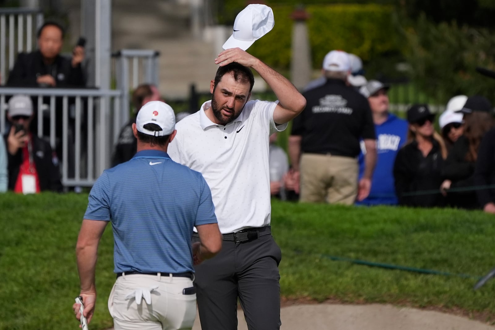 Scottie Scheffler, right, and Rory McIlroy, of Northern Ireland, shake hands after finishing on the 18th hole of the South Course at Torrey Pines during the final round of the Genesis Invitational golf tournament Sunday, Feb. 16, 2025, in San Diego. (AP Photo/Gregory Bull)