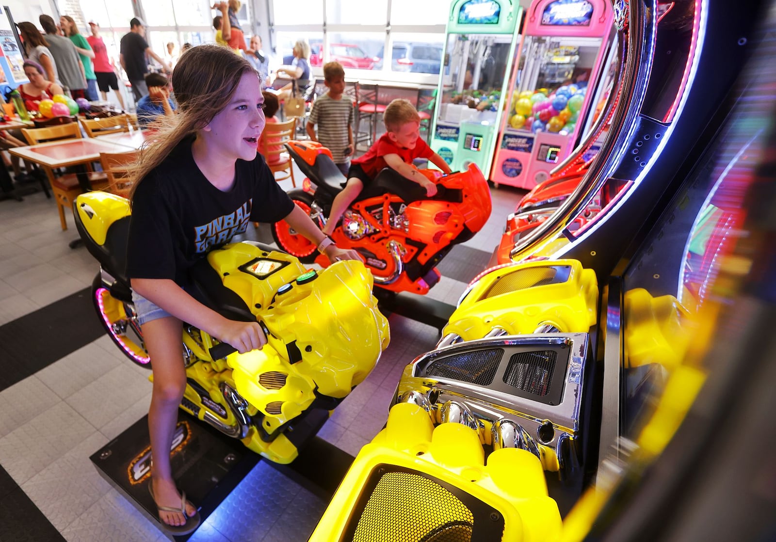 Jasmine Watkins, 11, and Dominic Watkins, 6, ride on a motorcycle game inside the new expansion at Pinball Garage. They've doubled their size and added 30 more games and a dining area. NICK GRAHAM/STAFF