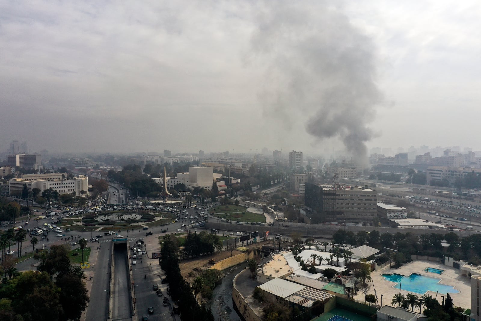 FILE - Smoke billows in the background as residents and opposition fighters celebrate in a central square after opposition forces took control of Damascus, Syria, on Sunday, Dec. 8, 2024. (AP Photo/Ghaith Alsayed, File)