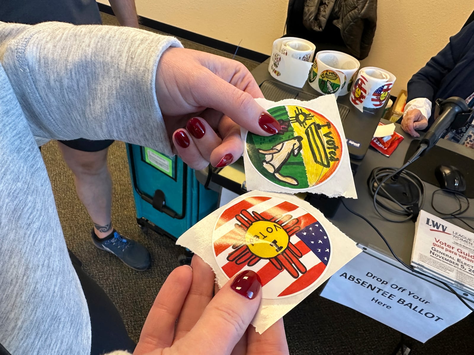 A voter holds a pair of I Voted stickers that were designed by students before signing in to cast a ballot at an early voting center in Albuquerque, N.M., on Wednesday, Oct. 30, 2024. (AP Photo/Susan Montoya Bryan)