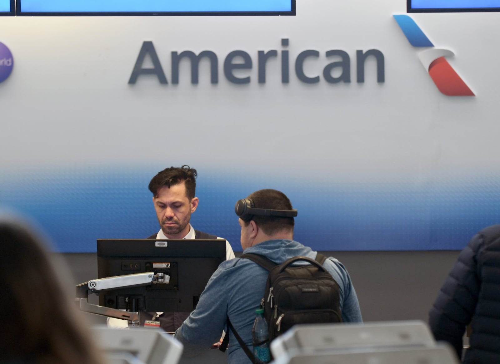 An American Airlines employee checks in a passenger at Denver International Airport on Friday, March 14, 2025, in Denver. (AP Photo/ Thomas Peipert)