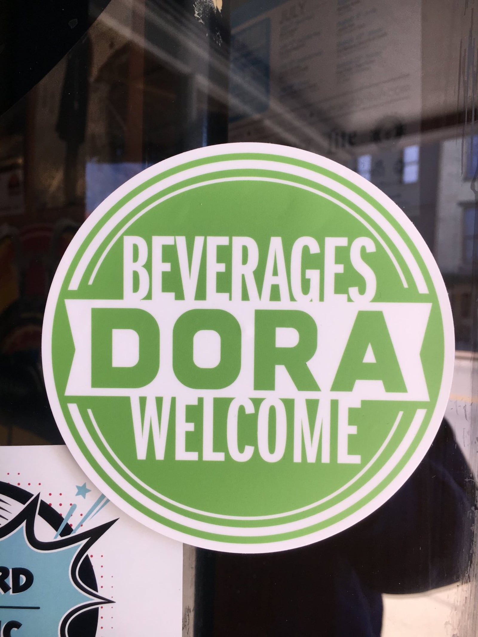 This decal, now on a Hamilton business, indicates that people are welcome to shop inside with adult drinks. The signs are part of the city’s new Downtown Outdoor Refreshment Area program, which launches Thursday. MIKE RUTLEDGE/STAFF