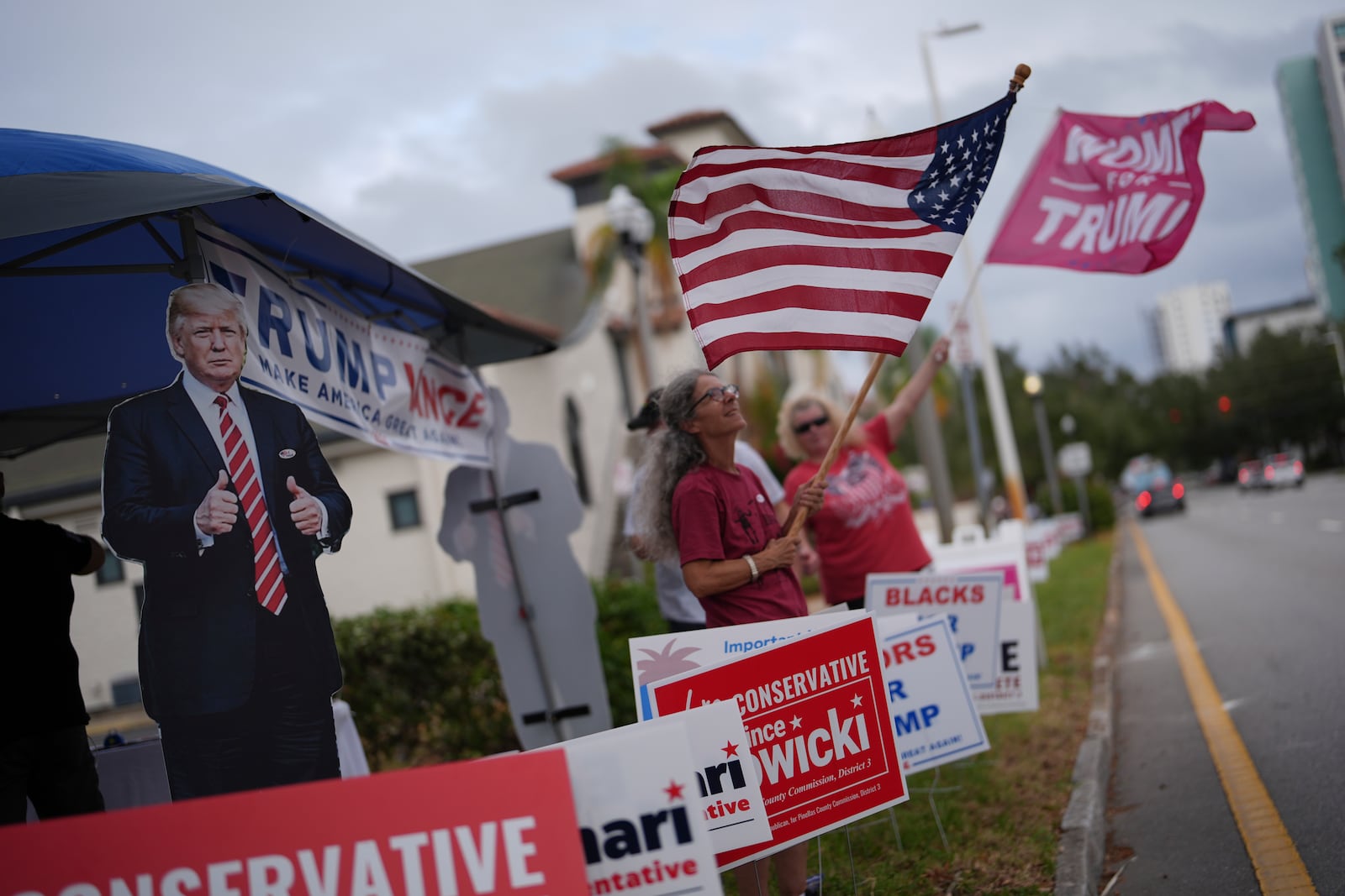 Supporters of Republican presidential nominee former President Donald Trump wave flags outside a polling place at the Coliseum in downtown St. Petersburg, Fla., on Election Day, Tuesday, Nov. 5, 2024. (AP Photo/Rebecca Blackwell)