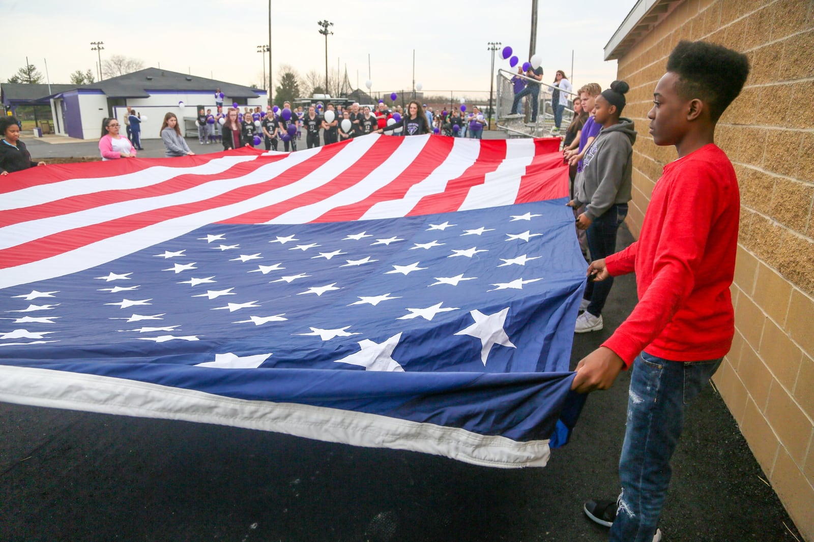 Middletown student LeRon Colson helps hold the flag during Opening Day ceremonies for the Middies baseball and softball teams at the newly renovated Lefferson Park complex Monday. GREG LYNCH/STAFF