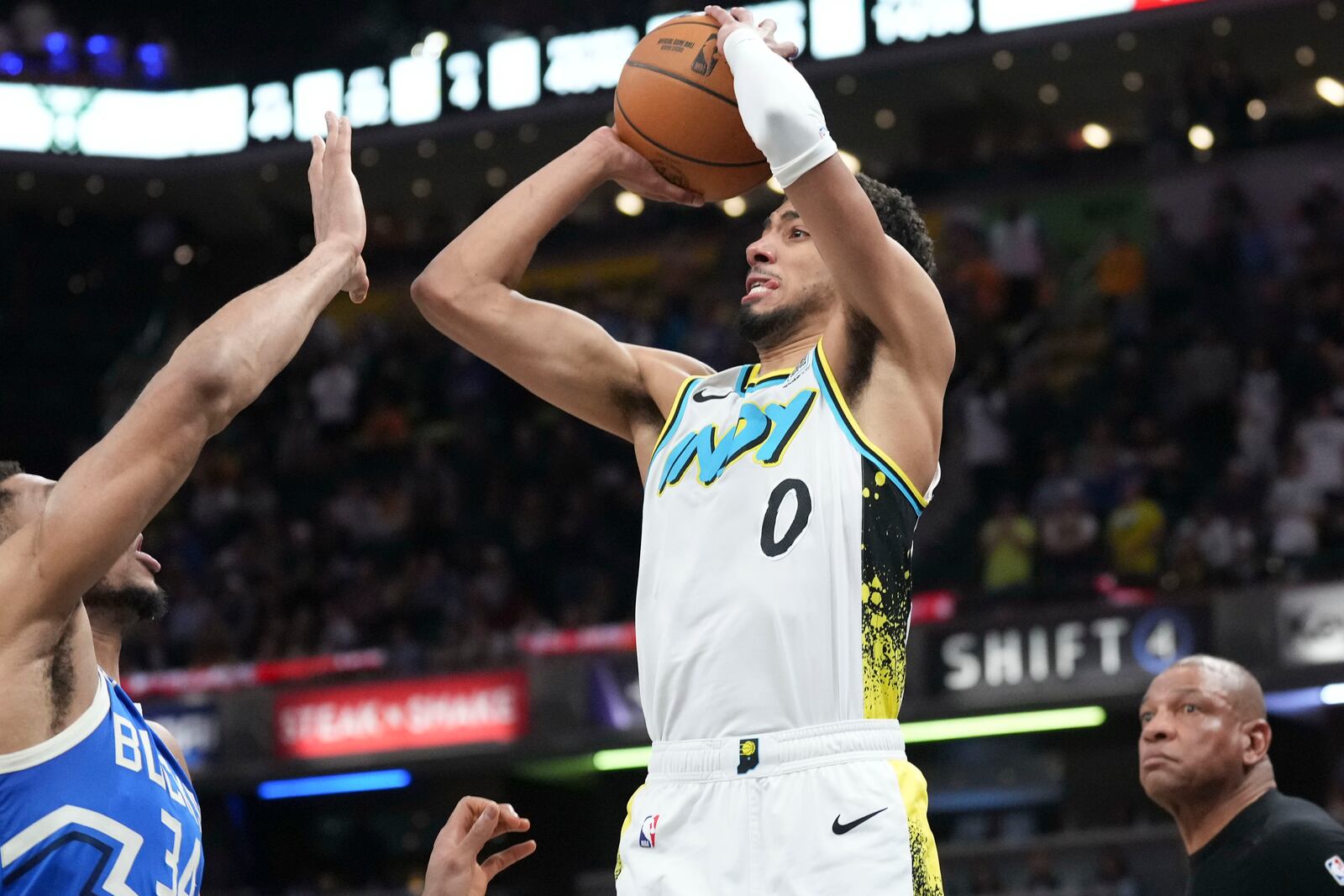 Indiana Pacers guard Tyrese Haliburton (0) shoots a three-point shot over Milwaukee Bucks forward Giannis Antetokounmpo (34) to tie the game late in the second half of an NBA basketball game in Indianapolis, Tuesday, March 11, 2025. (AP Photo/AJ Mast)