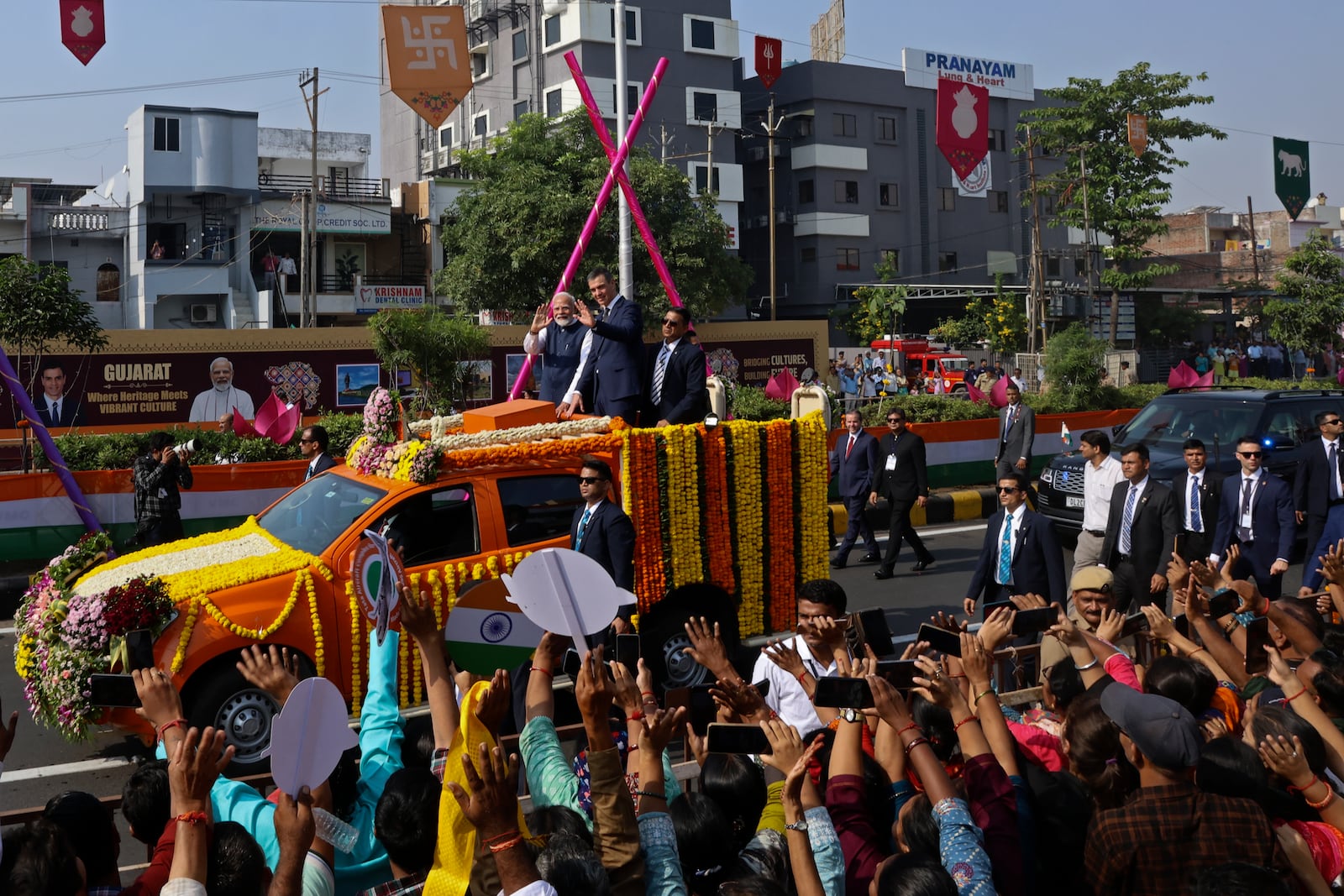 Indian Prime Minister Narendra Modi, center left, and his Spanish counterpart Pedro Sanchez, center right, wave to greet people from a vehicle in Vadodara, India, Monday, Oct. 28, 2024. (AP Photo)