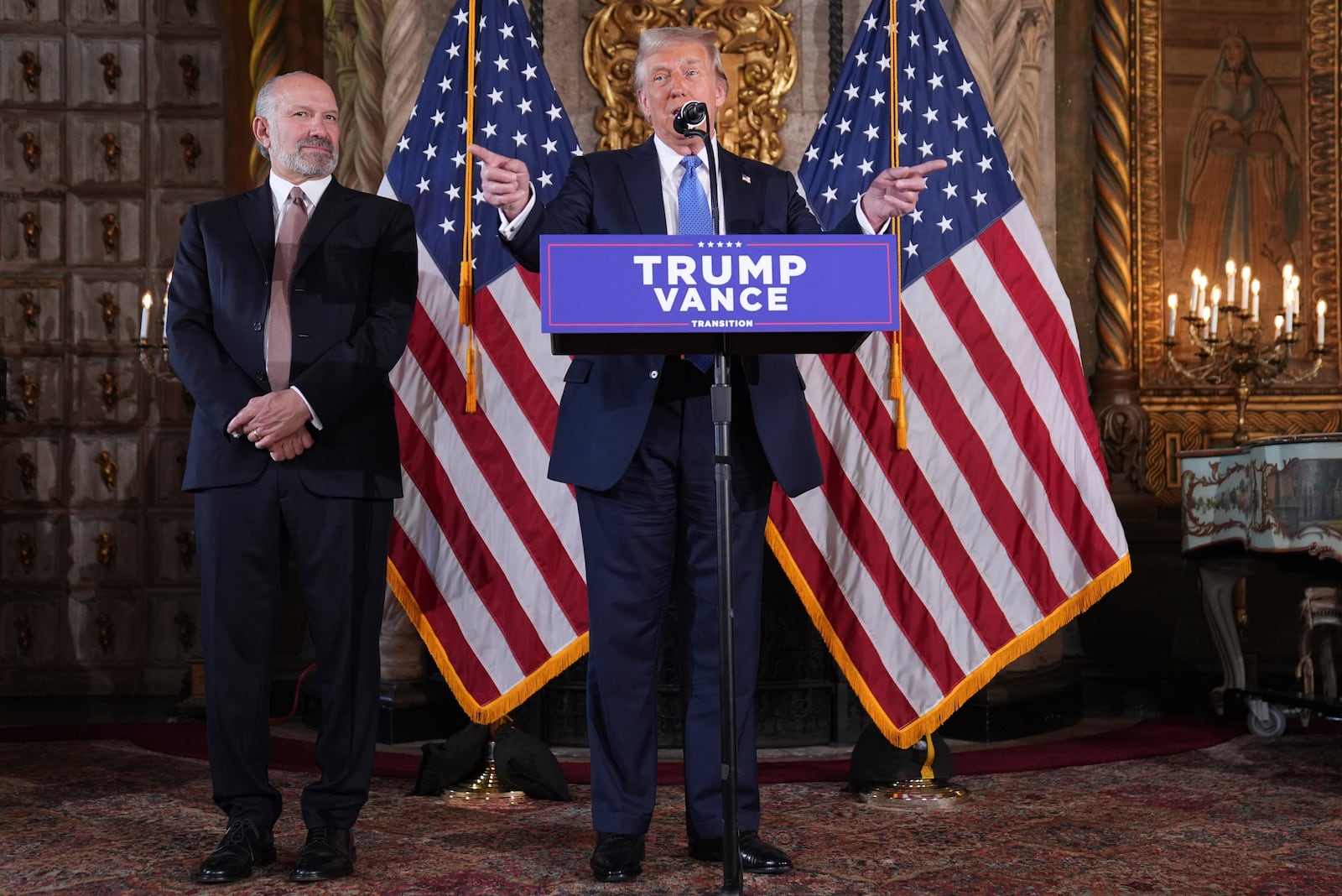 President-elect Donald Trump speaks during a news conference at Mar-a-Lago, Monday, Dec. 16, 2024, in Palm Beach, Fla., as Commerce Secretary nominee Howard Lutnick listens. (AP Photo/Evan Vucci)