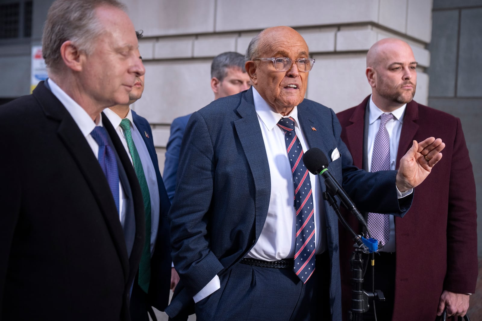 Rudy Giuliani, center, speaks to reporters after leaving federal court in Washington, Friday, Jan. 10, 2025. (AP Photo/Mark Schiefelbein)