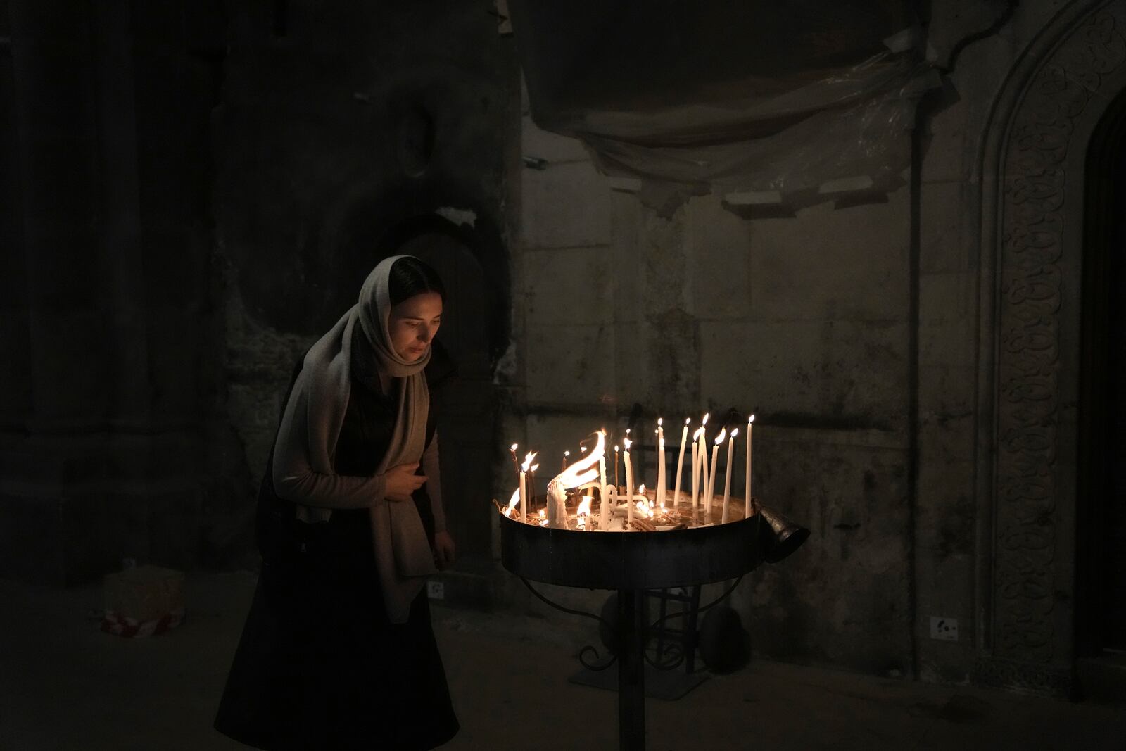 A woman lights candles in the Church of the Holy Sepulchre, where many Christians believe Jesus was crucified, buried and rose from the dead, in the Old City of Jerusalem, Tuesday, Jan. 28, 2025. (AP Photo/Mahmoud Illean)