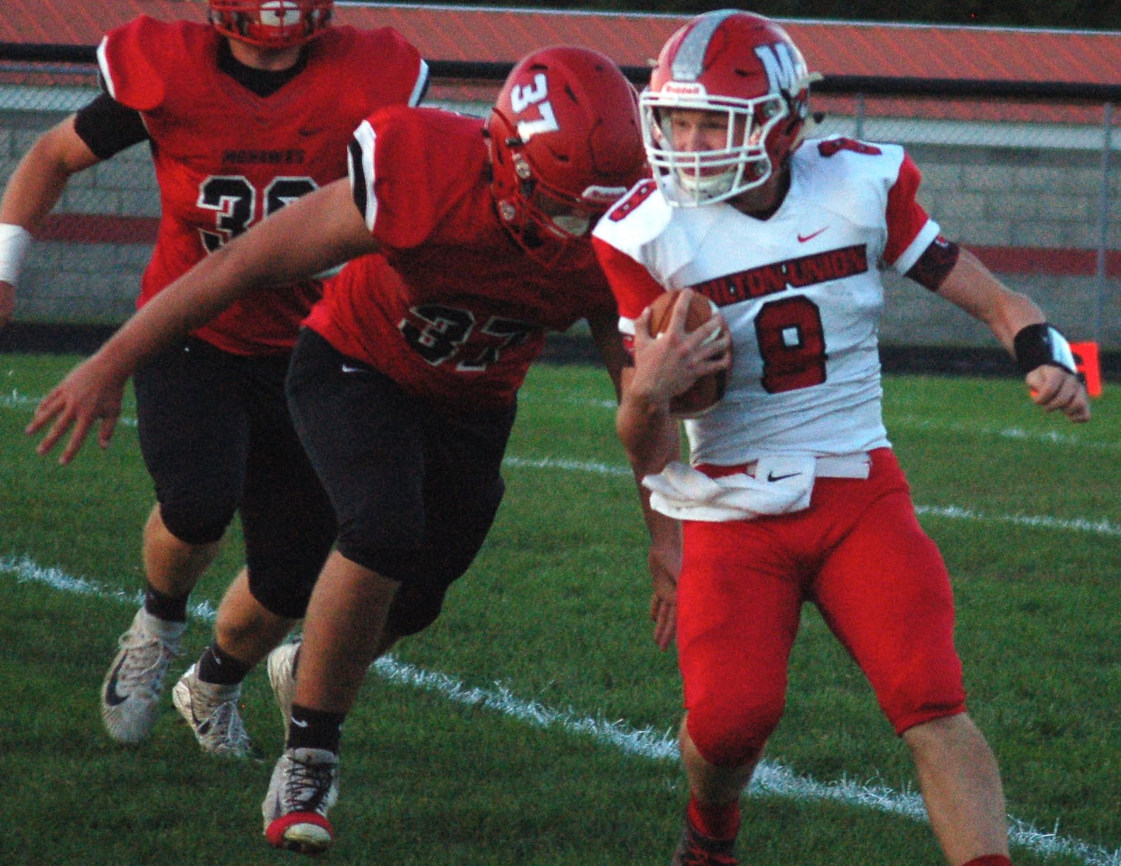 Milton-Union quarterback William Morris tries to avoid Madison’s Tanner Limon on Sept. 29 at Brandenburg Field in Madison Township. The host Mohawks won 46-0. CONTRIBUTED PHOTO BY JOHN CUMMINGS