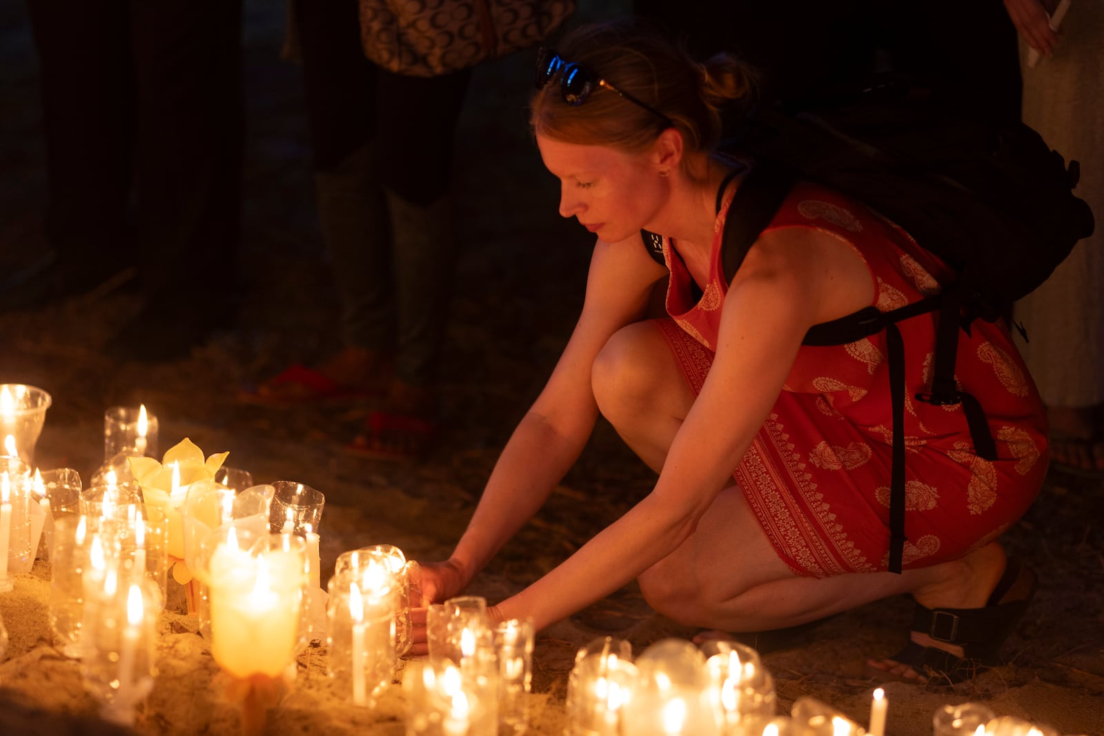 A woman adjusts a candle during a candle light vigil on the 20th anniversary of the2004 Indian Ocean tsunami, at Tsunami Memorial Park at Ban Nam Khem, Takuapa district of Phang Nga province, southern Thailand, Thursday, Dec. 26, 2024. (AP Photo/Wason Wanichakorn)