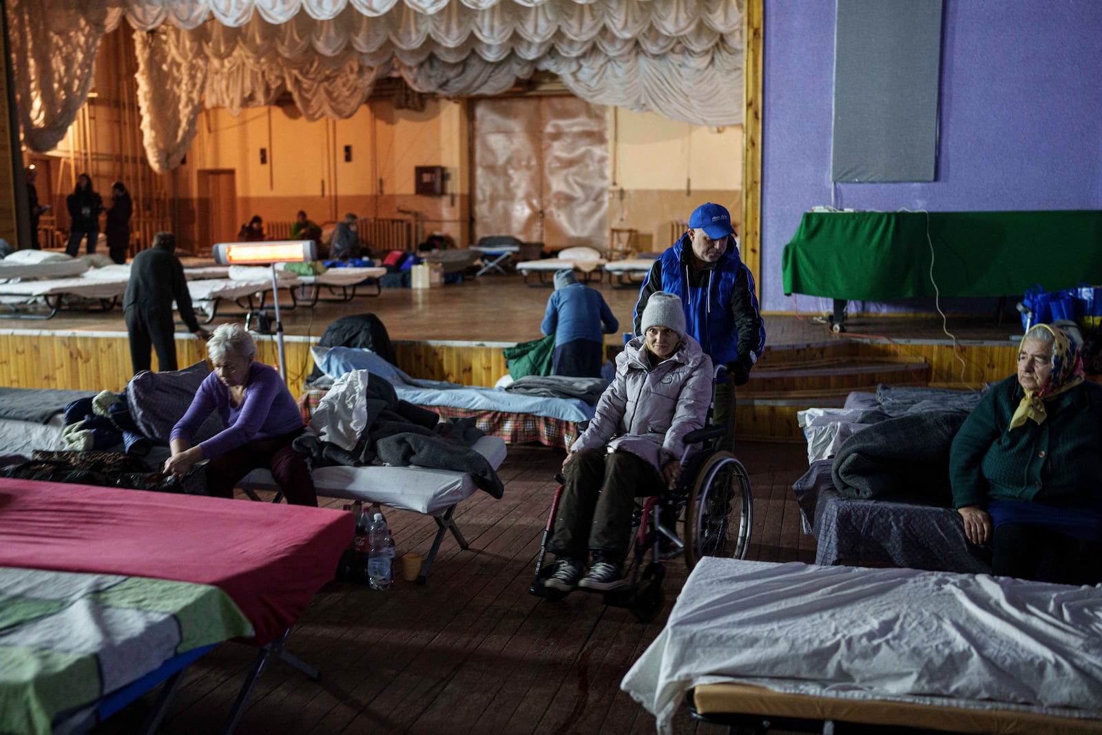 A volunteer helps a woman on a wheelchair at a center for displaced people in Pavlohrad, Ukraine, Saturday, Feb. 1, 2024. (AP Photo/Evgeniy Maloletka)