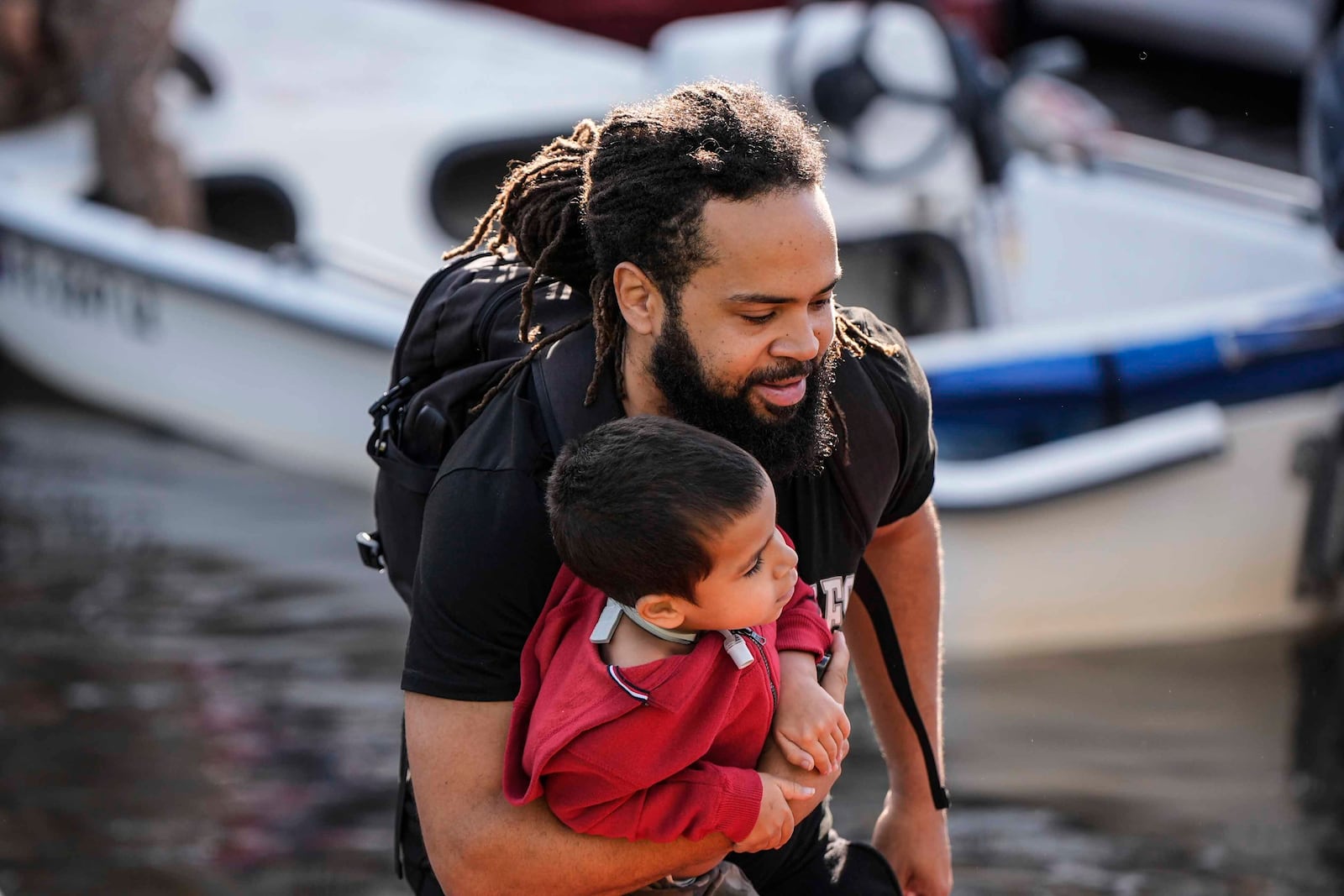 A man and child leave a rescue boar after high flood waters entered their apartment in the aftermath of Hurricane Milton, Thursday, Oct. 10, 2024, in Clearwater, Fla. (AP Photo/Mike Stewart)