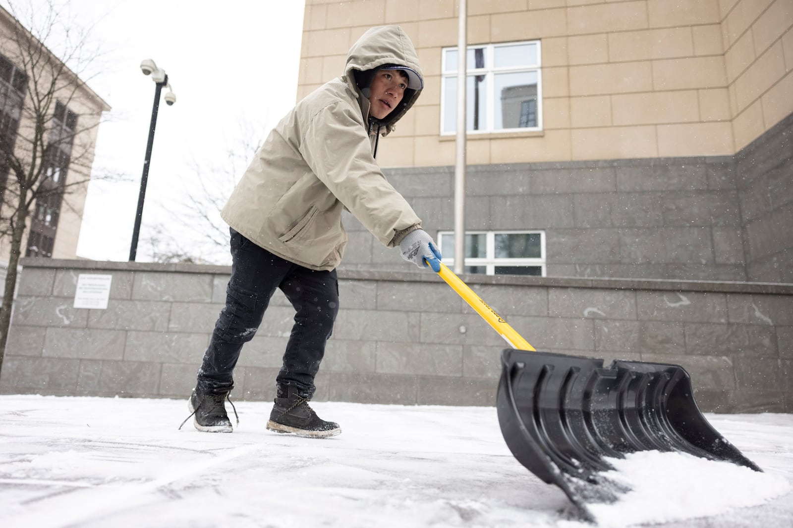 A person shovels snow on the sidewalk of East Broad St. in Richmond, Va., Wednesday, Feb. 19, 2025. (Mike Kropf/Richmond Times-Dispatch via AP)