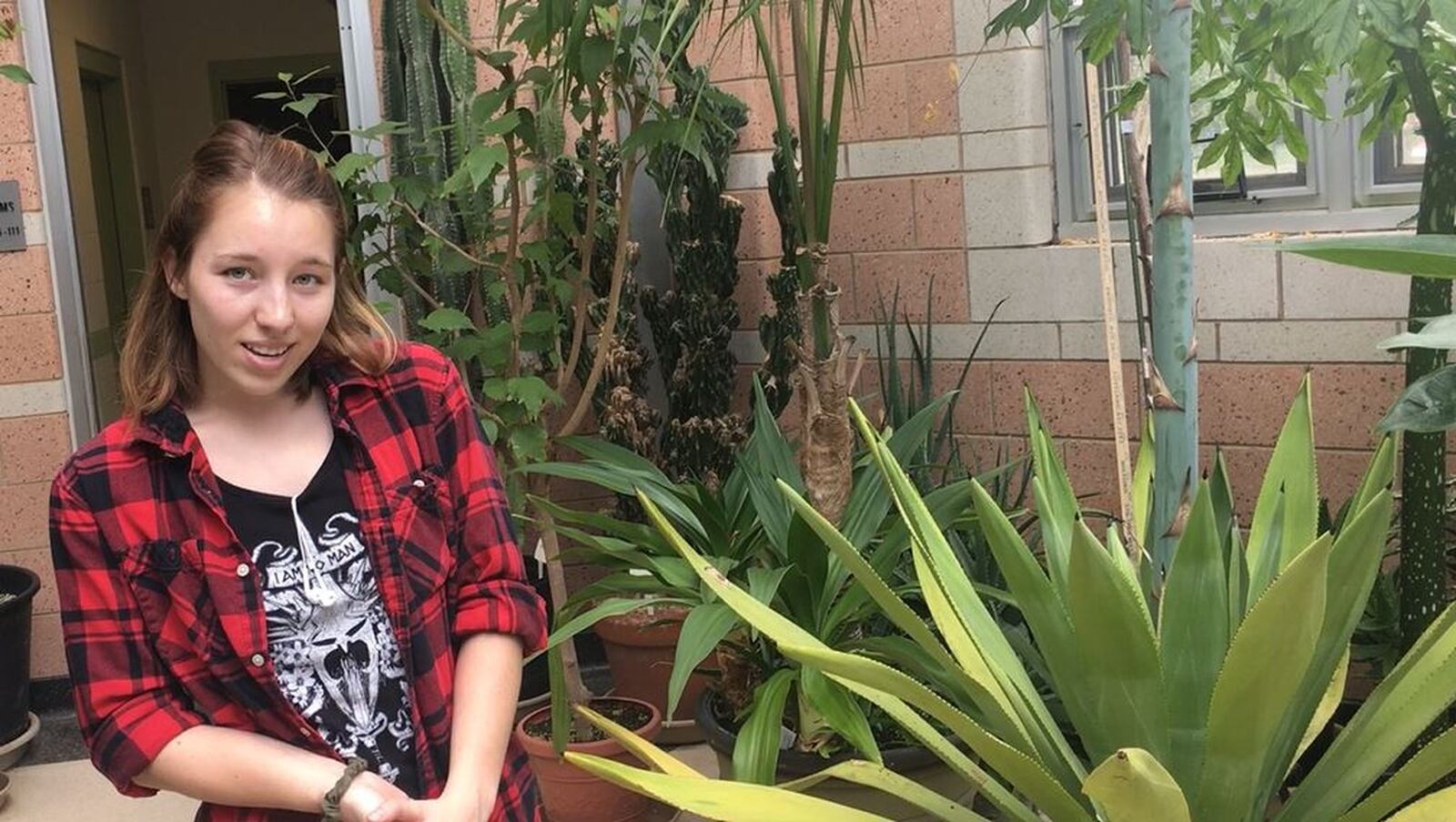 Emma Boggs of Fairfield, who has worked at the Conservatory on Miami University’s Hamilton campus for three years, is looking forward to the flowering of the agave plant next to her. MIKE RUTLEDGE/STAFF